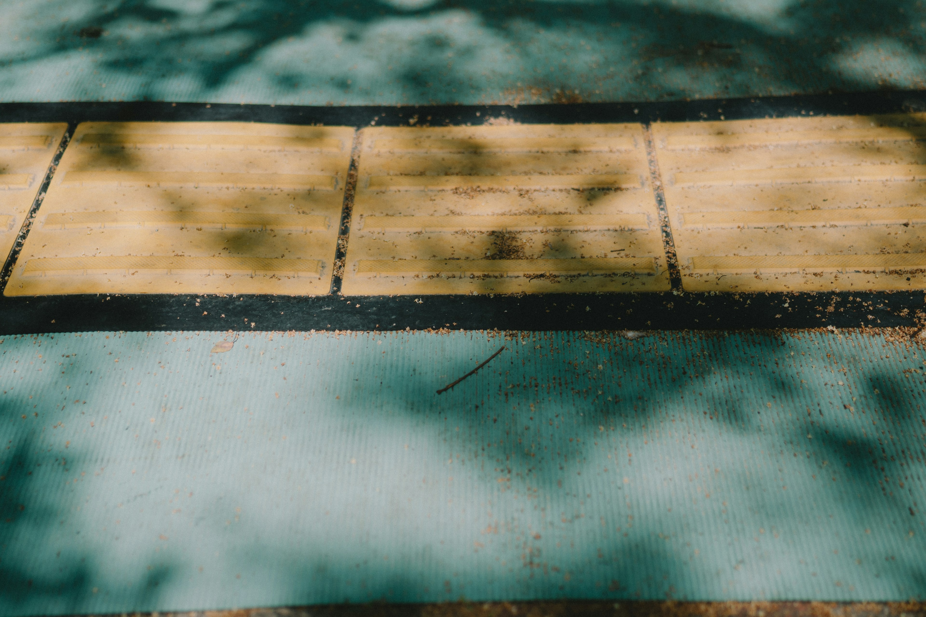 Une section de sol bleu avec des planches en bois jaunâtre et des ombres éparses