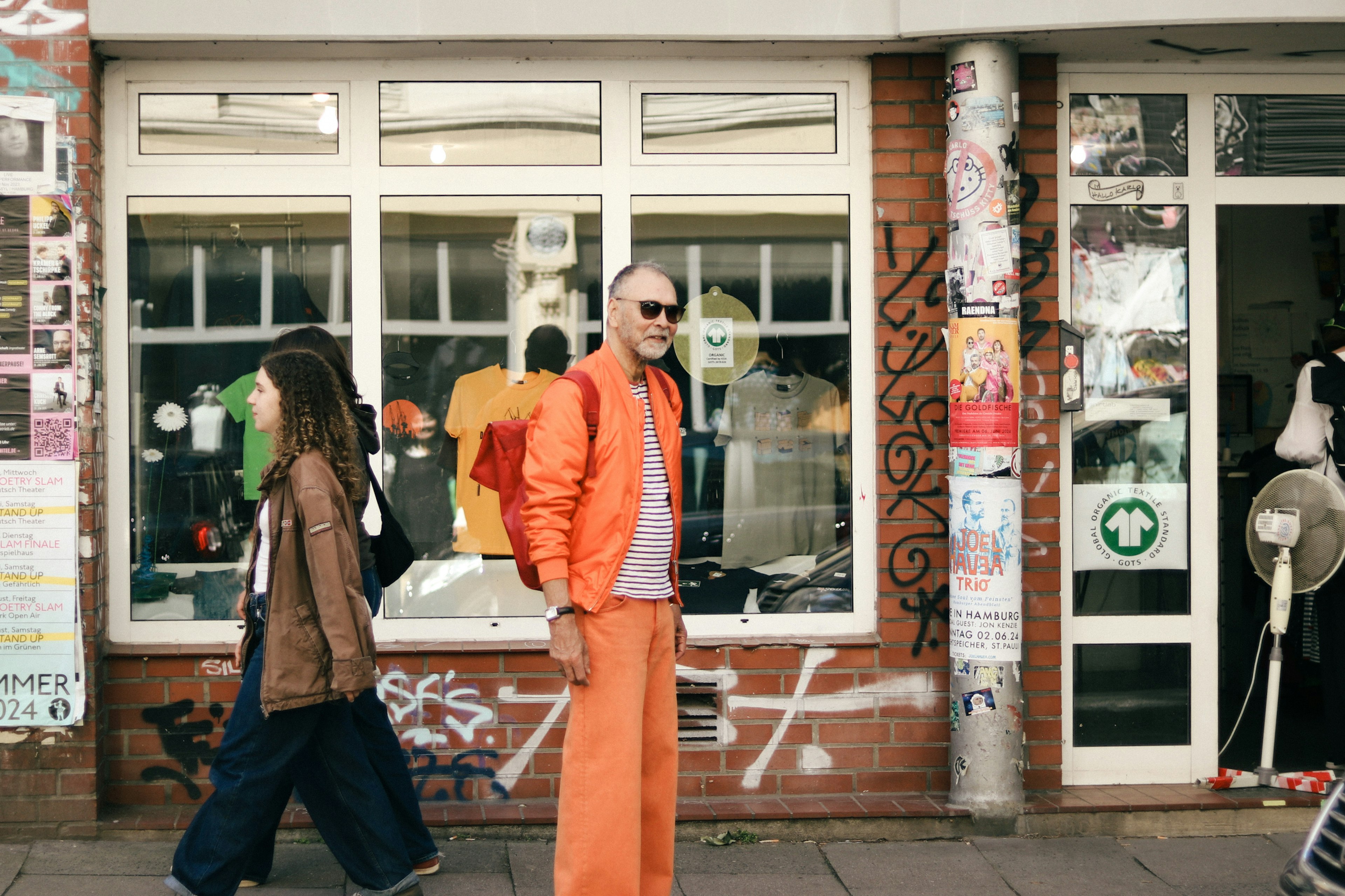 Ein Mann in orange und eine Frau in legerer Kleidung, die auf der Straße gehen