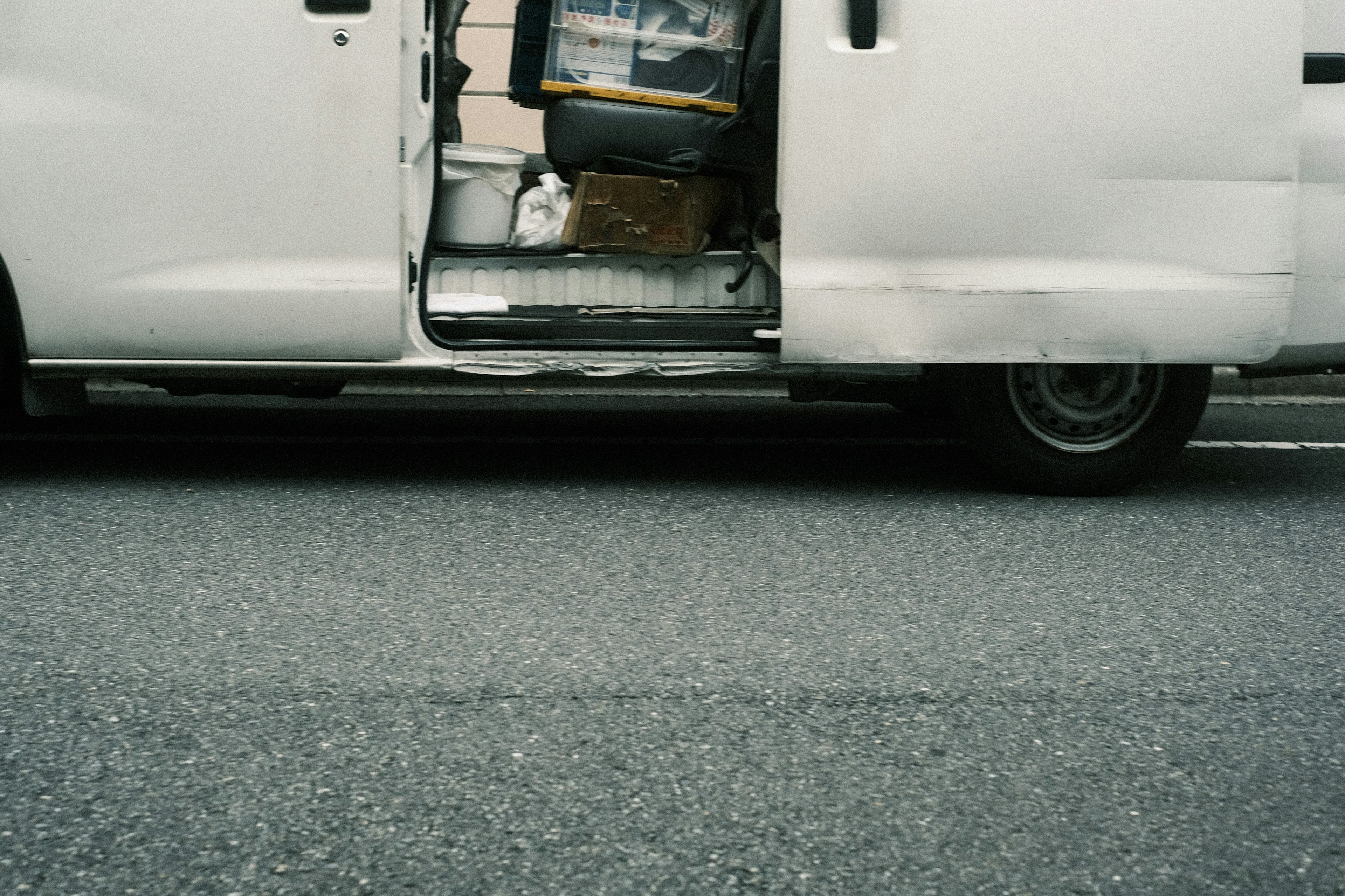 Ein Foto von einem weißen Van mit offener Tür, die Taschen und Kisten im Inneren auf der Straße zeigt