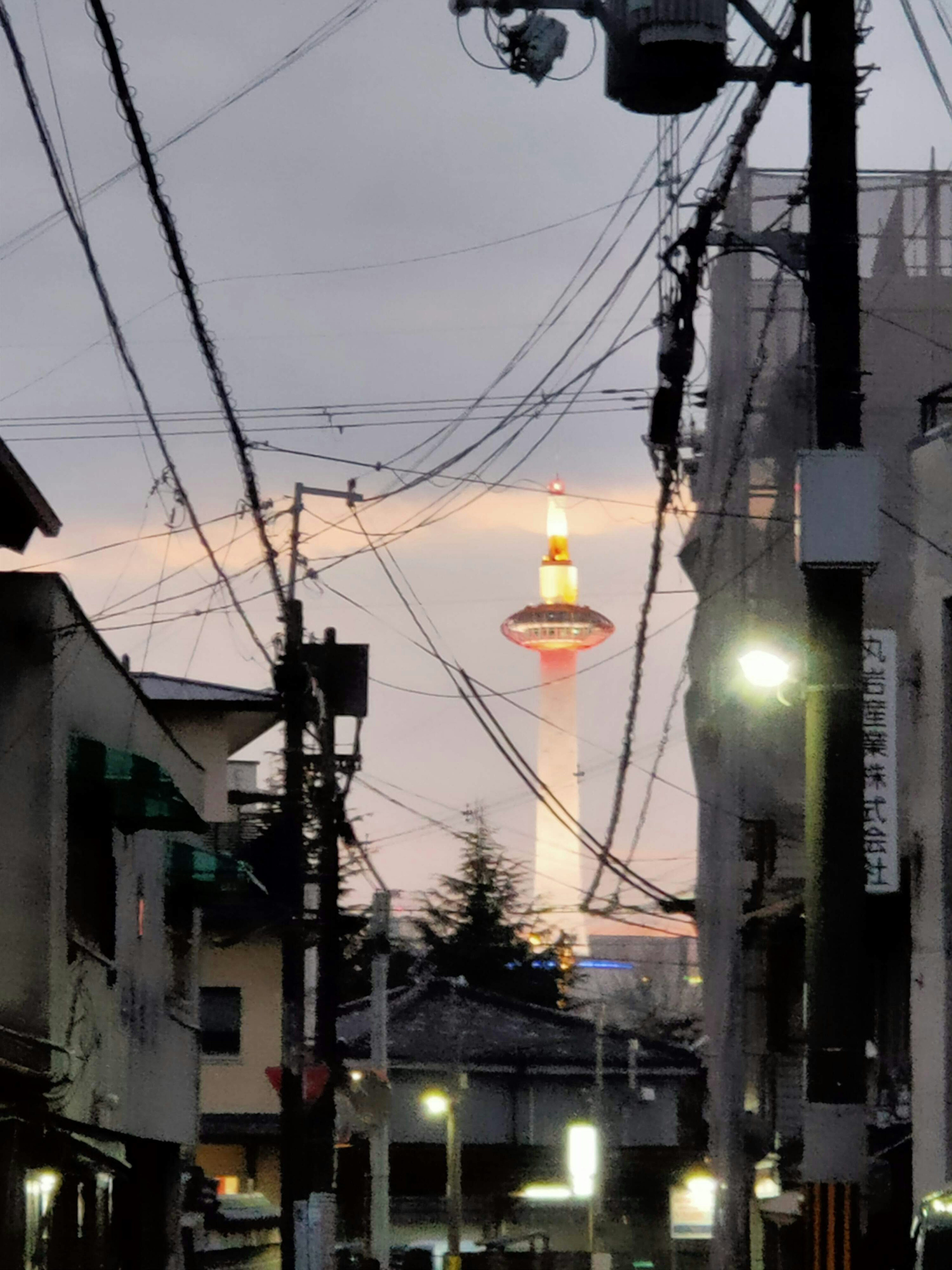 Kyoto Tower bei Dämmerung sichtbar mit Stadtstraßen und Stromleitungen