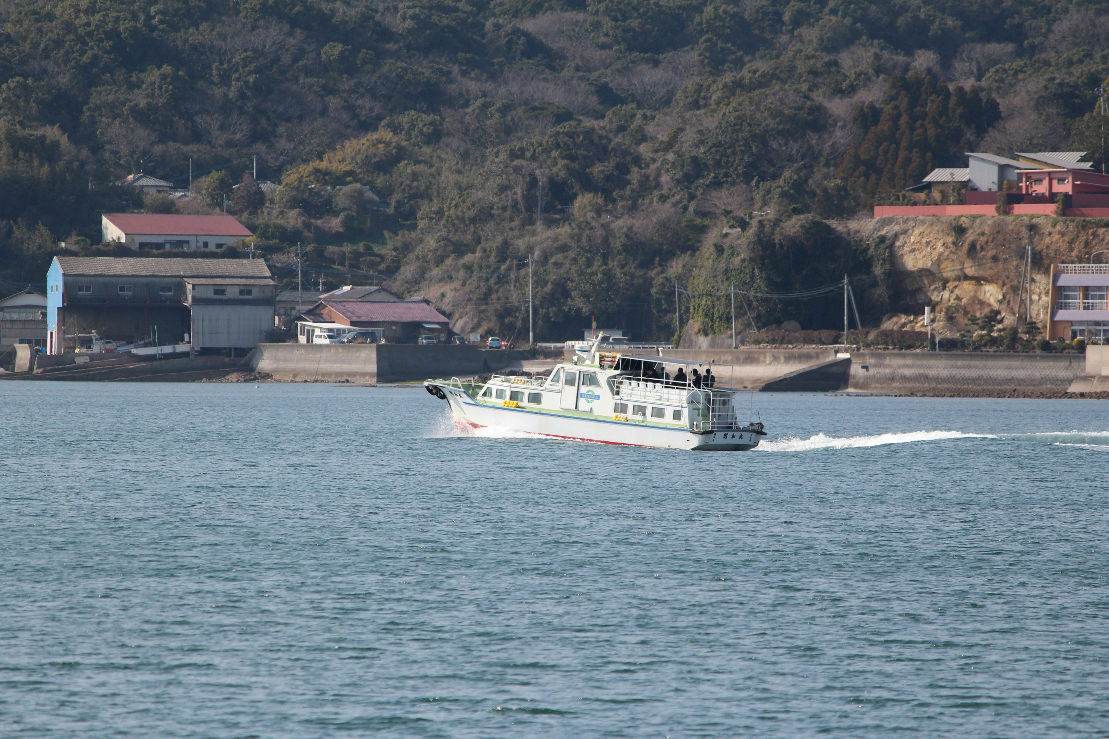 Small boat navigating across the water with buildings in the background