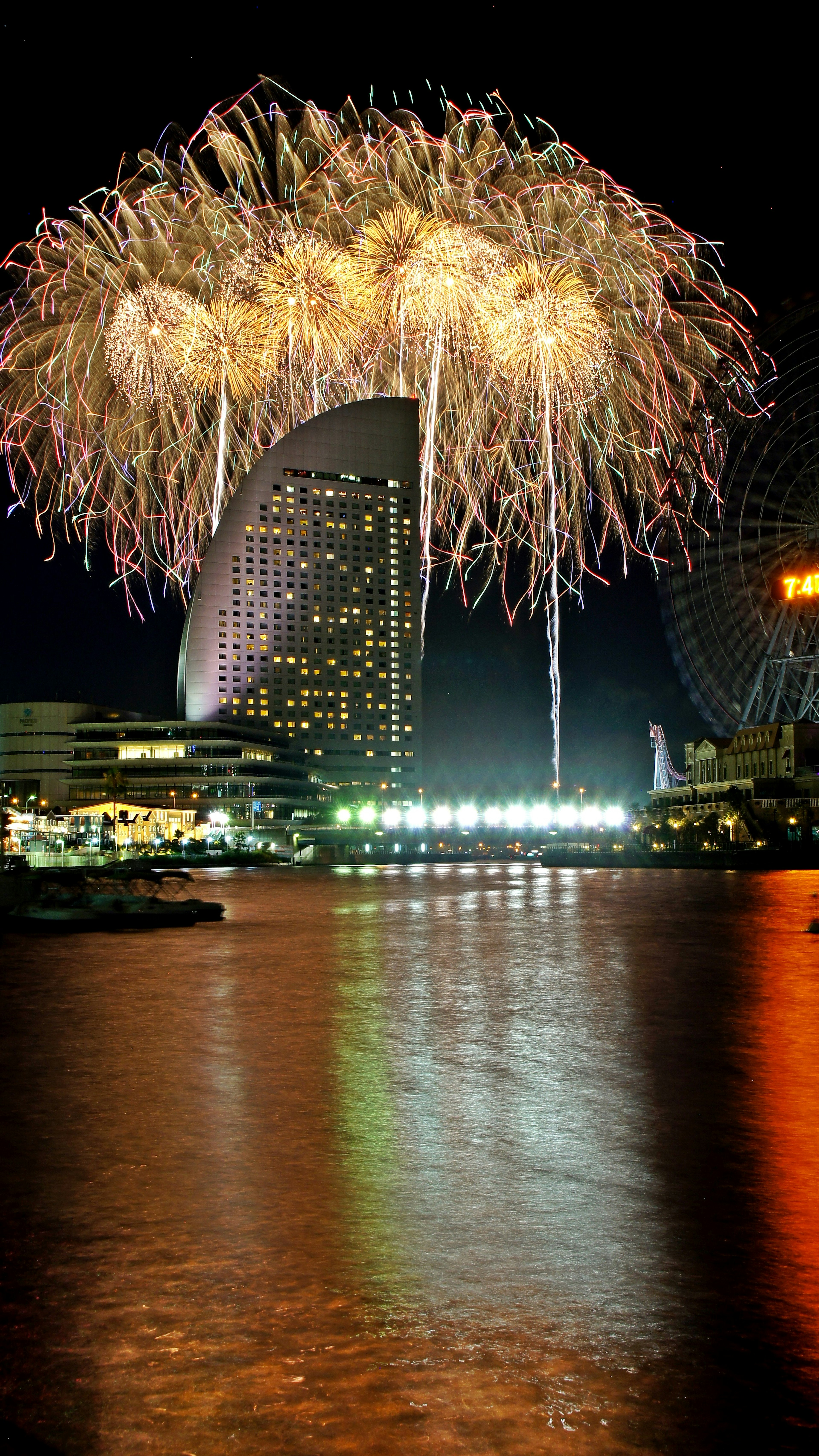 Fuochi d'artificio che illuminano il cielo notturno con riflessi sull'acqua