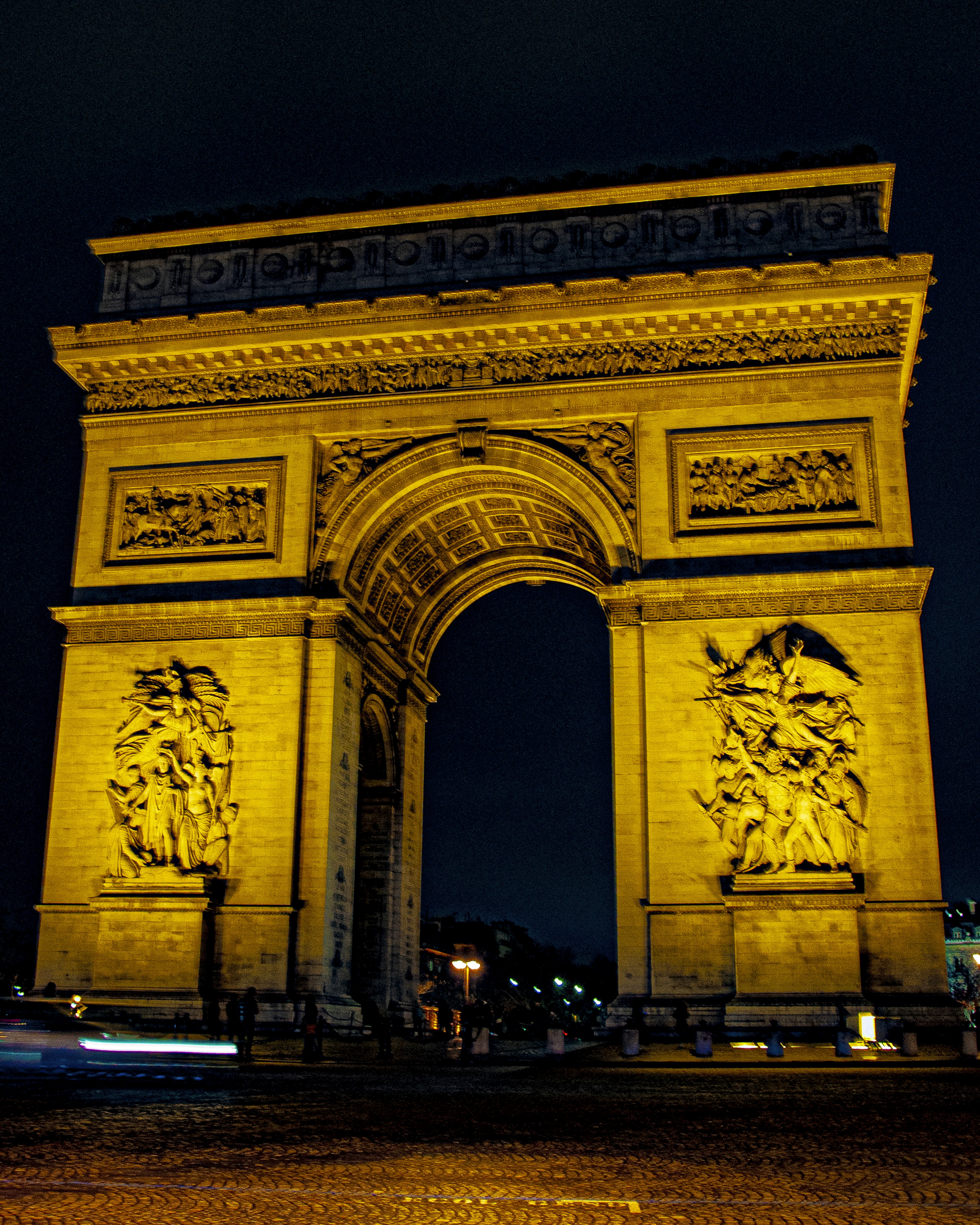 Gambar Arc de Triomphe yang diterangi di malam hari menampilkan pencahayaan emas