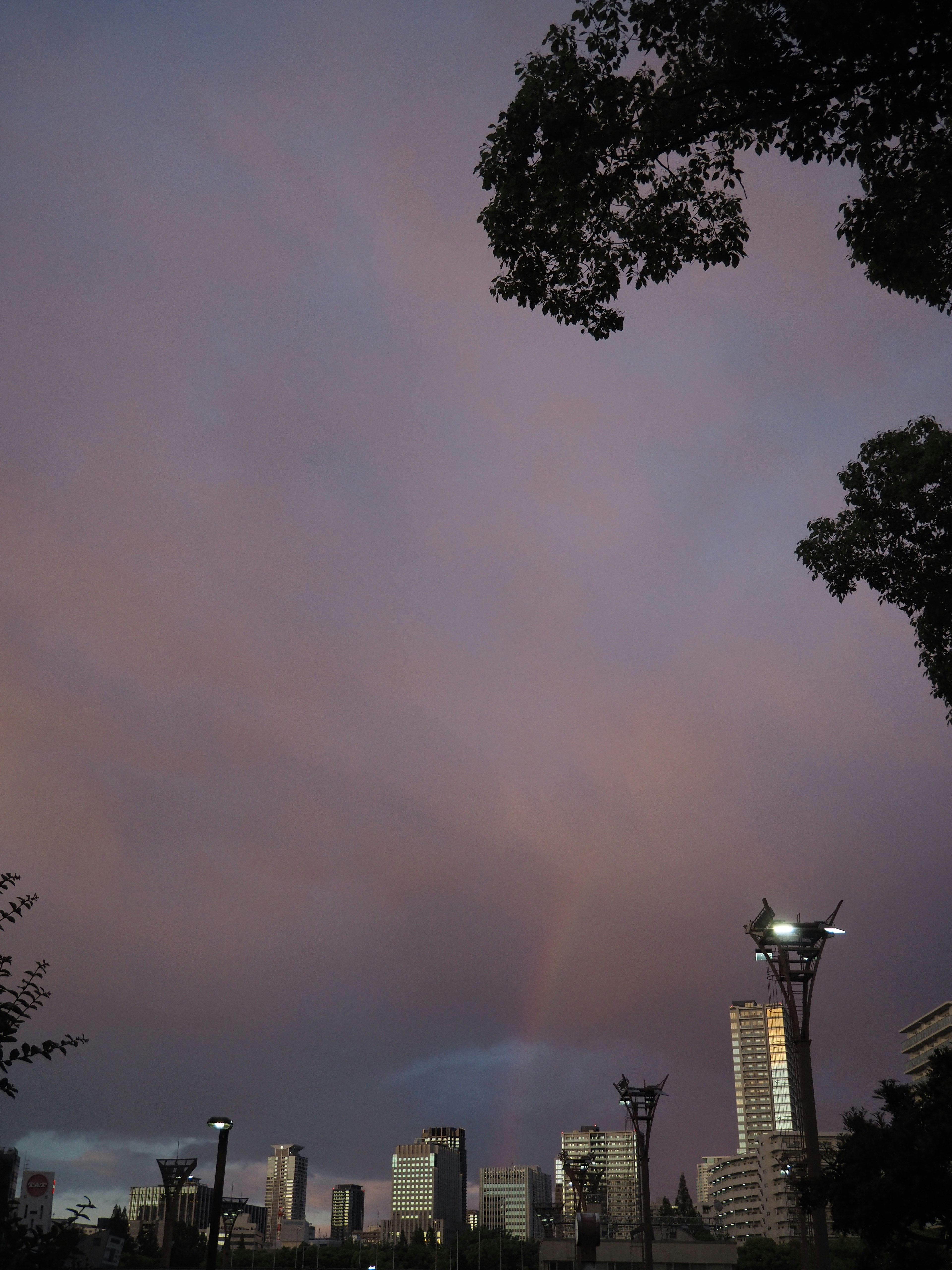 เส้นขอบฟ้าของเมืองที่มีสายรุ้งอยู่ใต้ท้องฟ้ายามพระอาทิตย์ตก