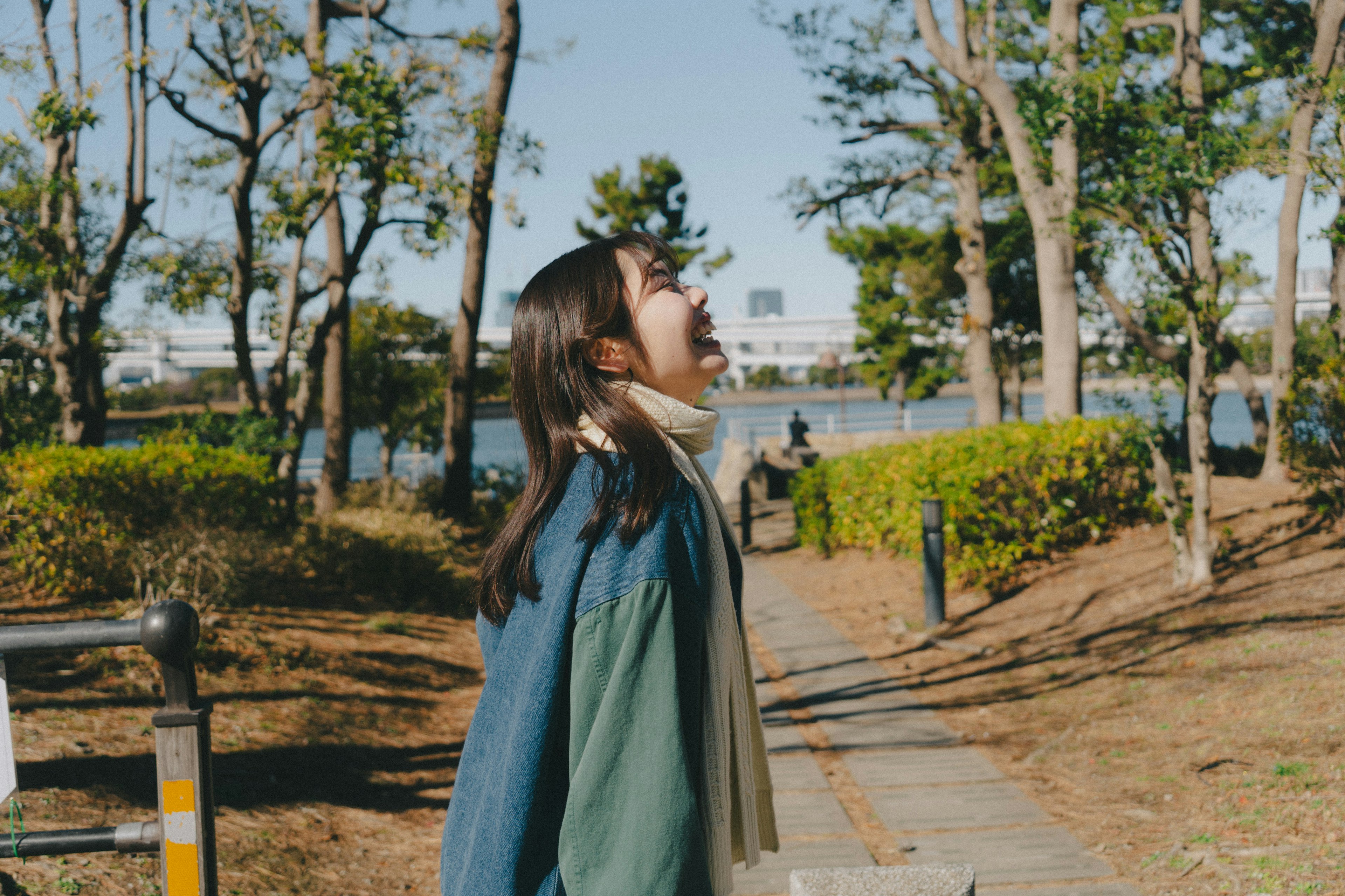 Woman looking up at the sky in a park surrounded by green trees and blue sky