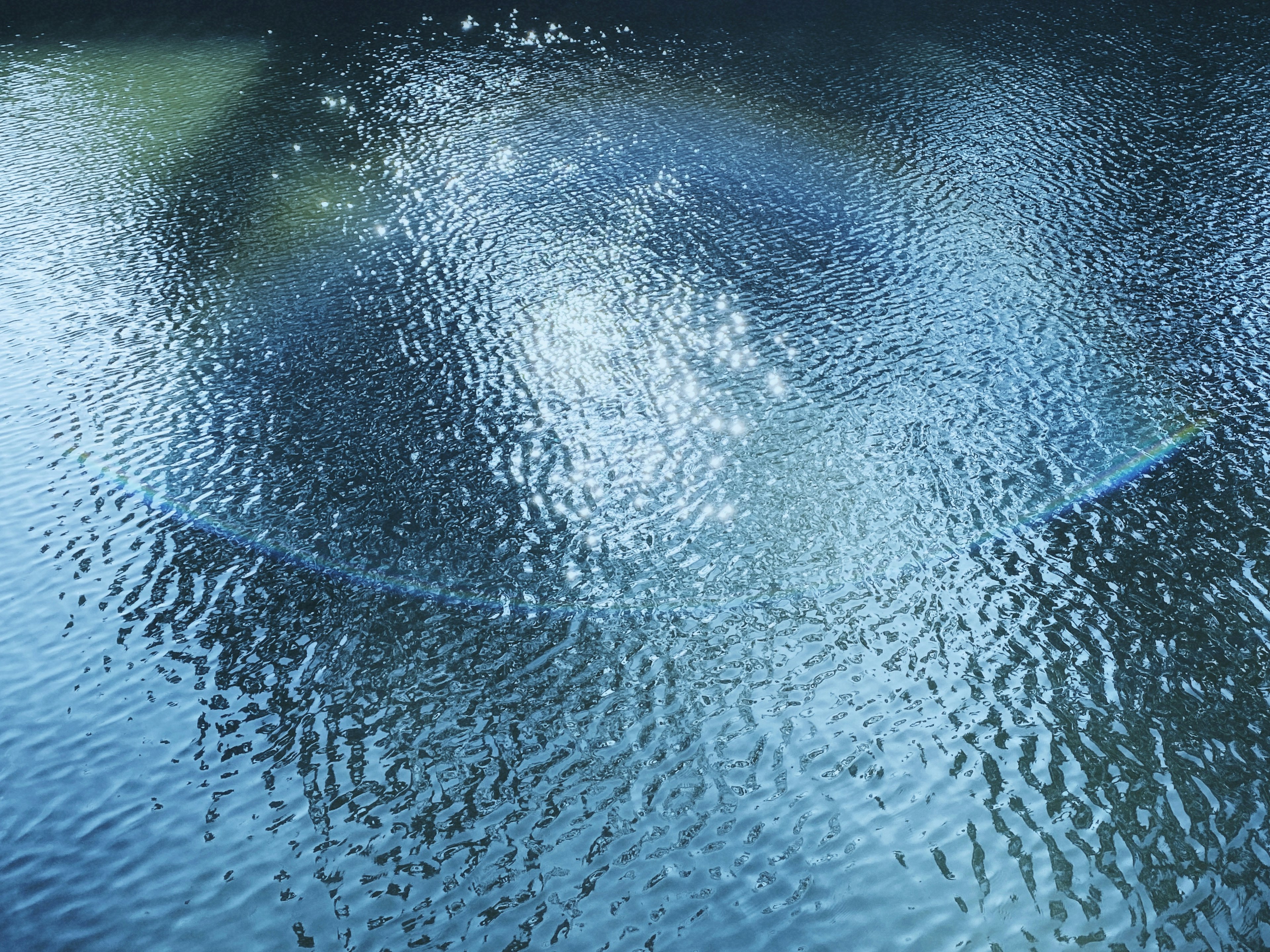 Image of a blue water surface with ripples and reflections of light