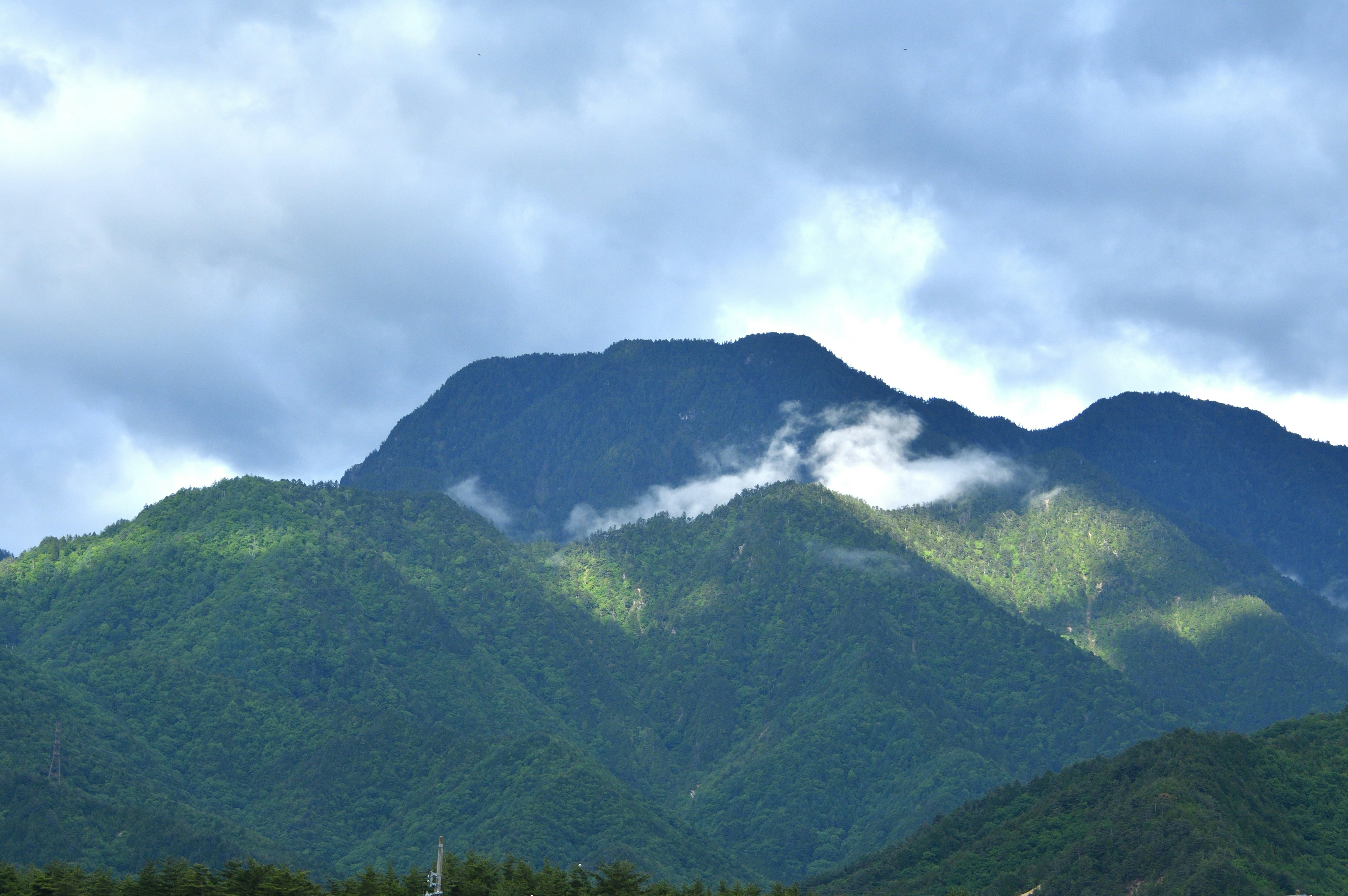 Scenic view of green mountains covered with clouds