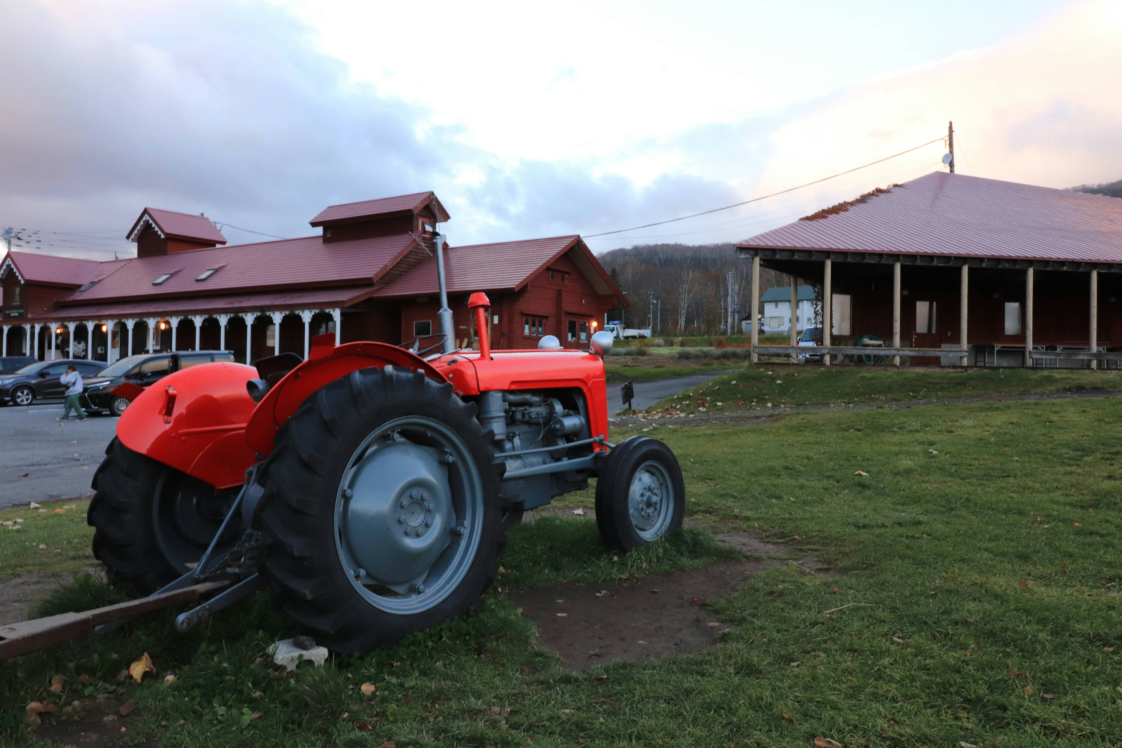 Red tractor parked on green grass near a rustic building