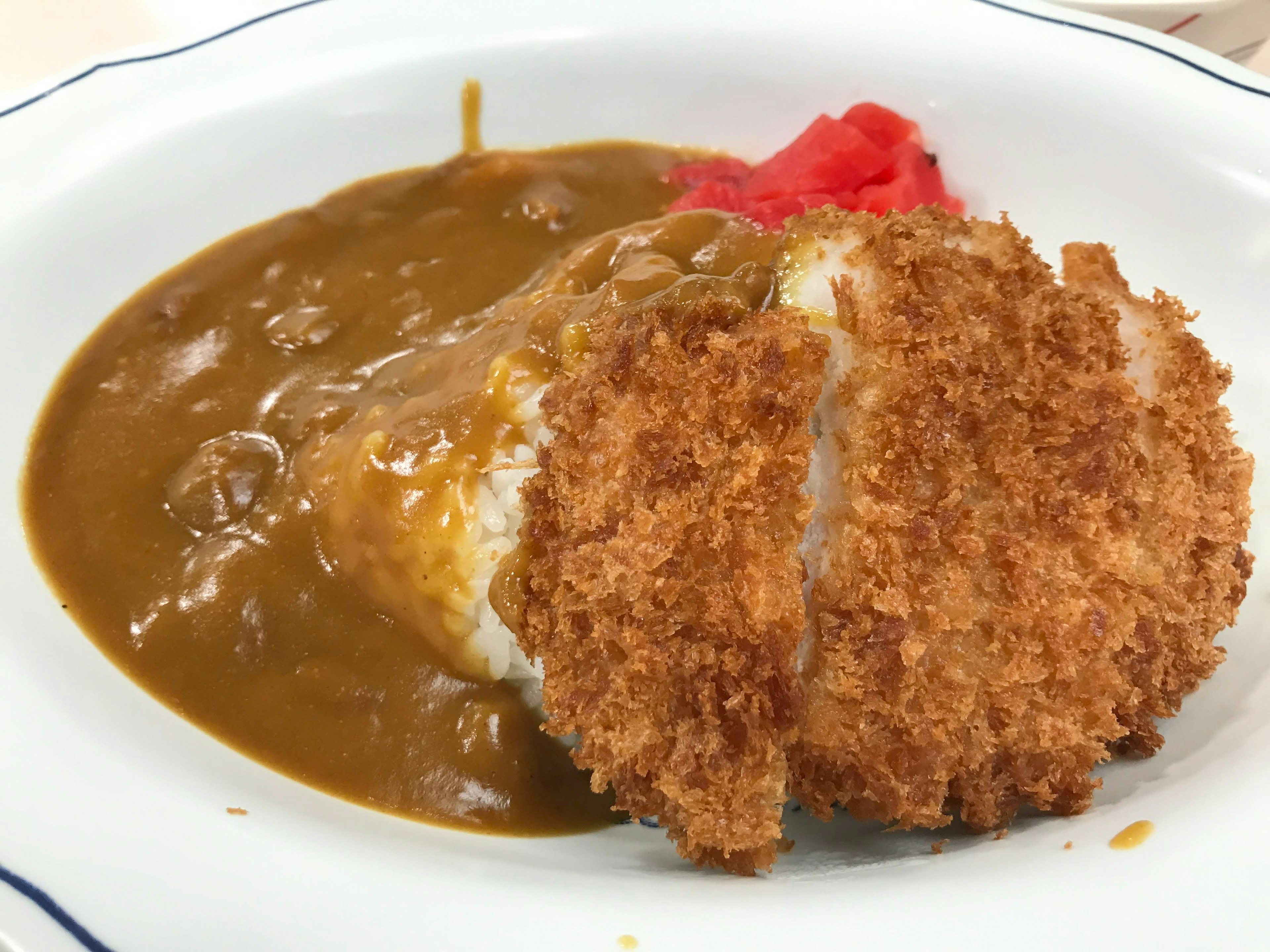 Piring katsu curry yang terdiri dari nasi dan potongan daging babi yang dibalut tepung roti