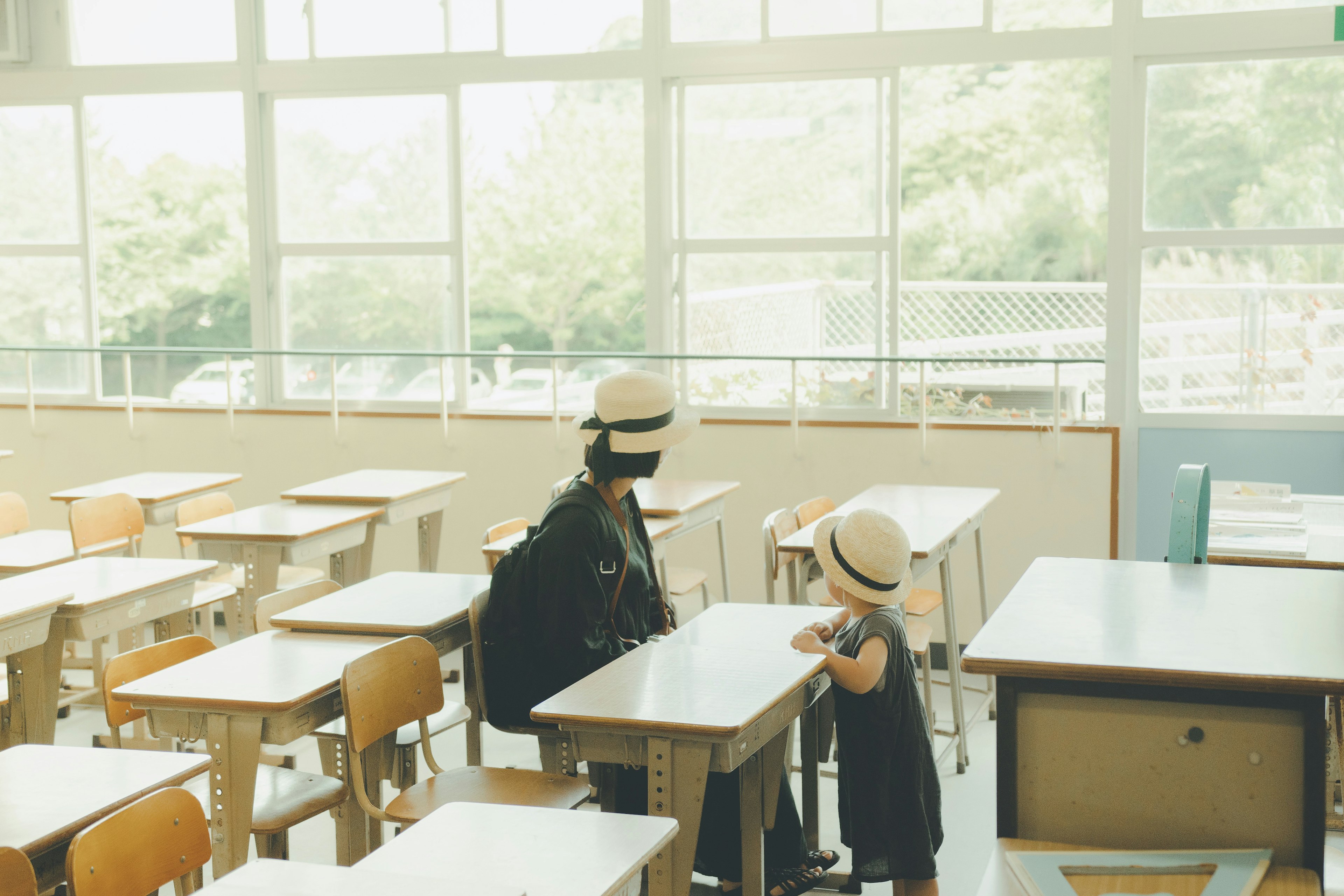 Un'aula luminosa con un adulto e un bambino che indossano cappelli seduti l'uno di fronte all'altro