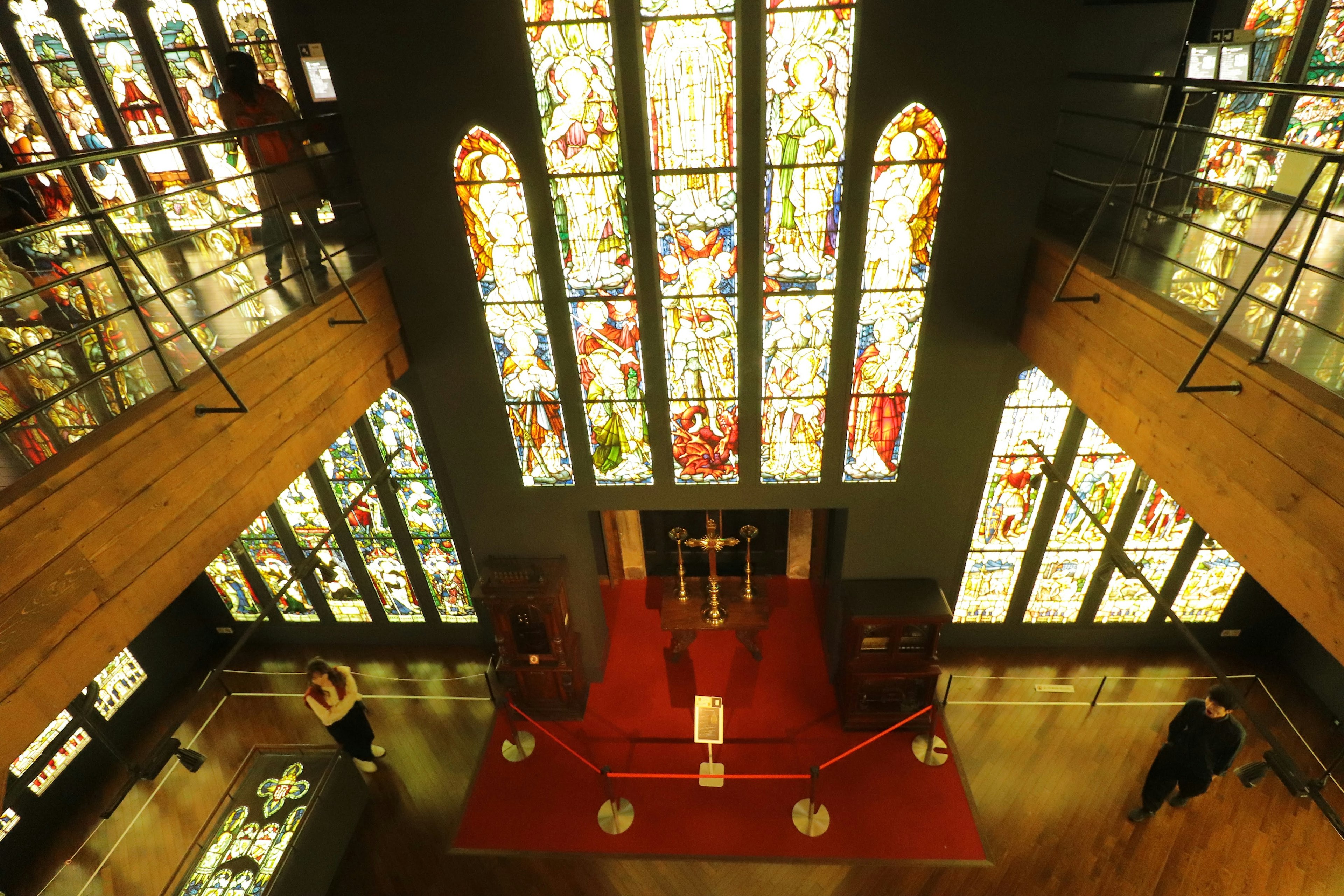 Vista interior de una iglesia con hermosas ventanas de vitrales alfombra roja y decoración de madera