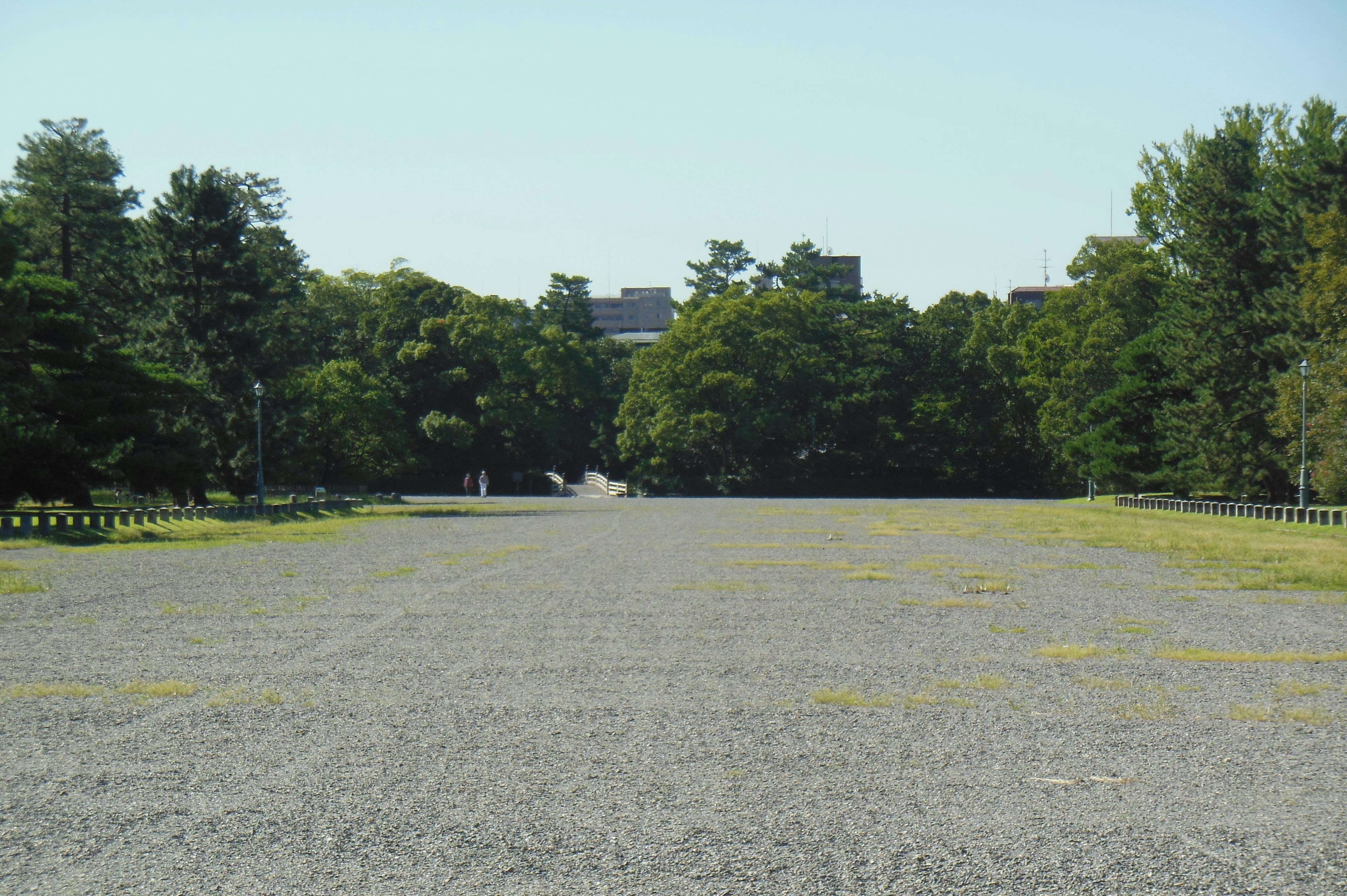 Expansive gravel area with lush green trees in the background