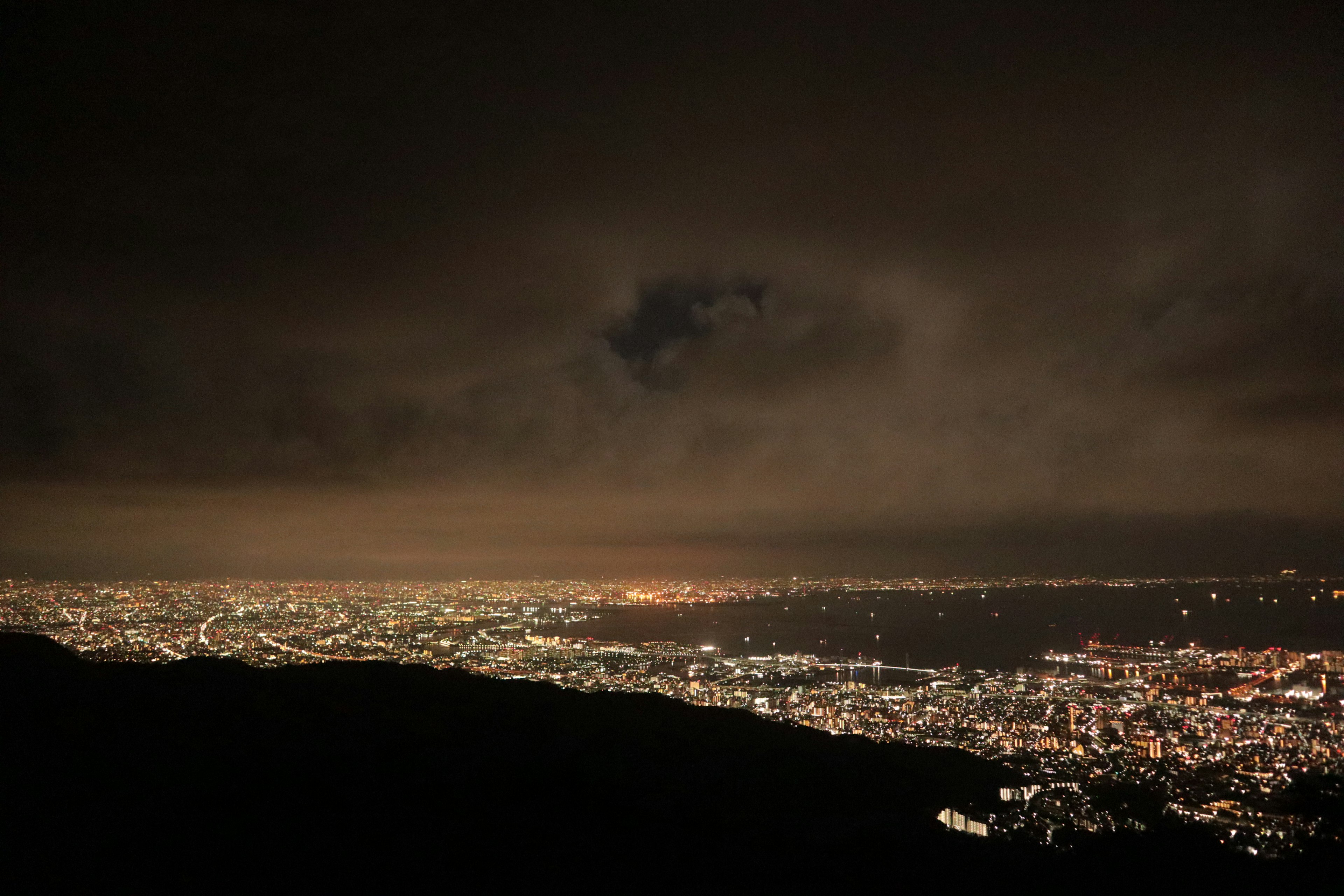 Vista notturna di una città illuminata da luci sotto un cielo nuvoloso