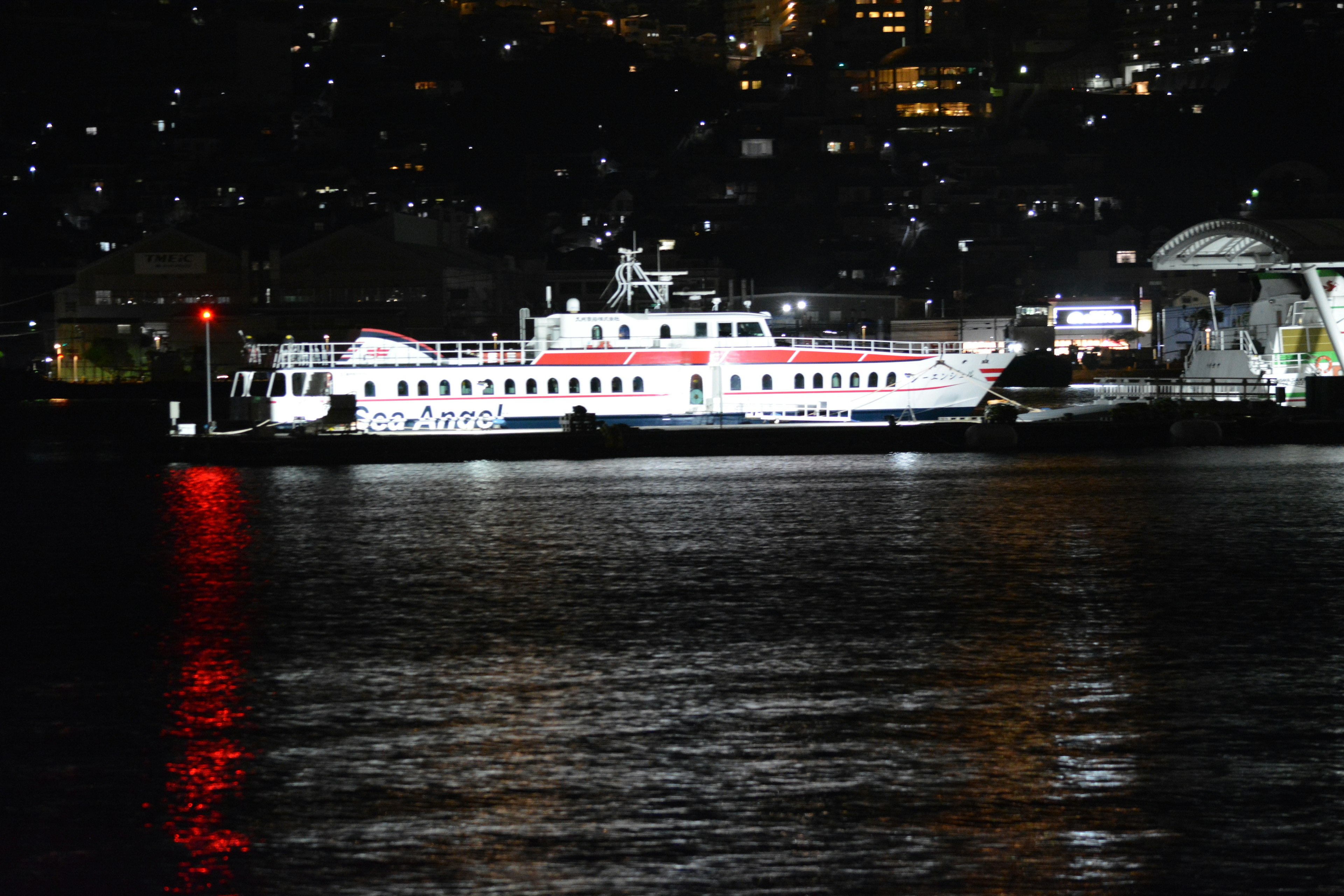 Beleuchtete Fähre auf dem Wasser bei Nacht mit Stadtansicht