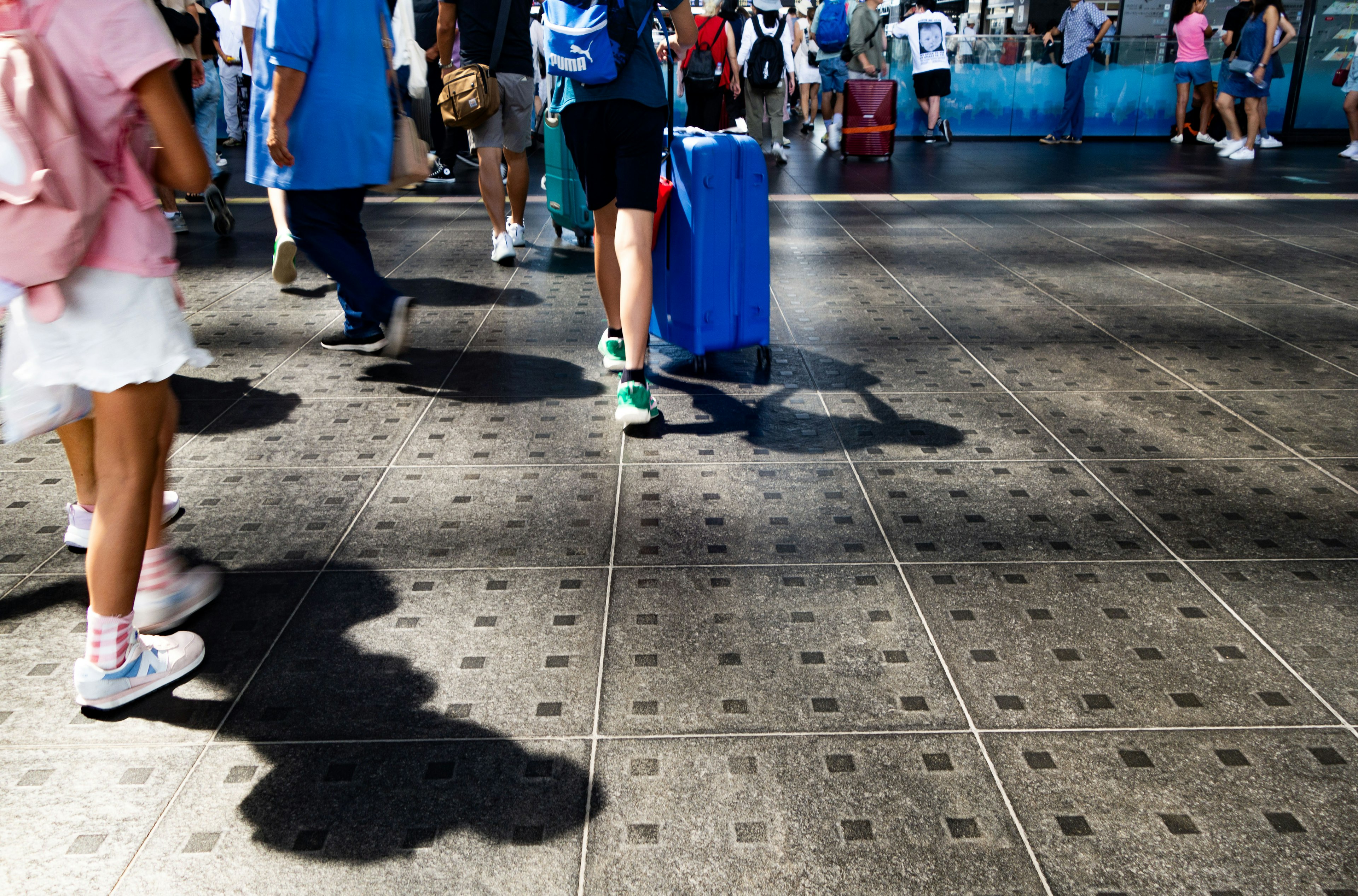 Busy street scene with people walking shadows cast on textured pavement