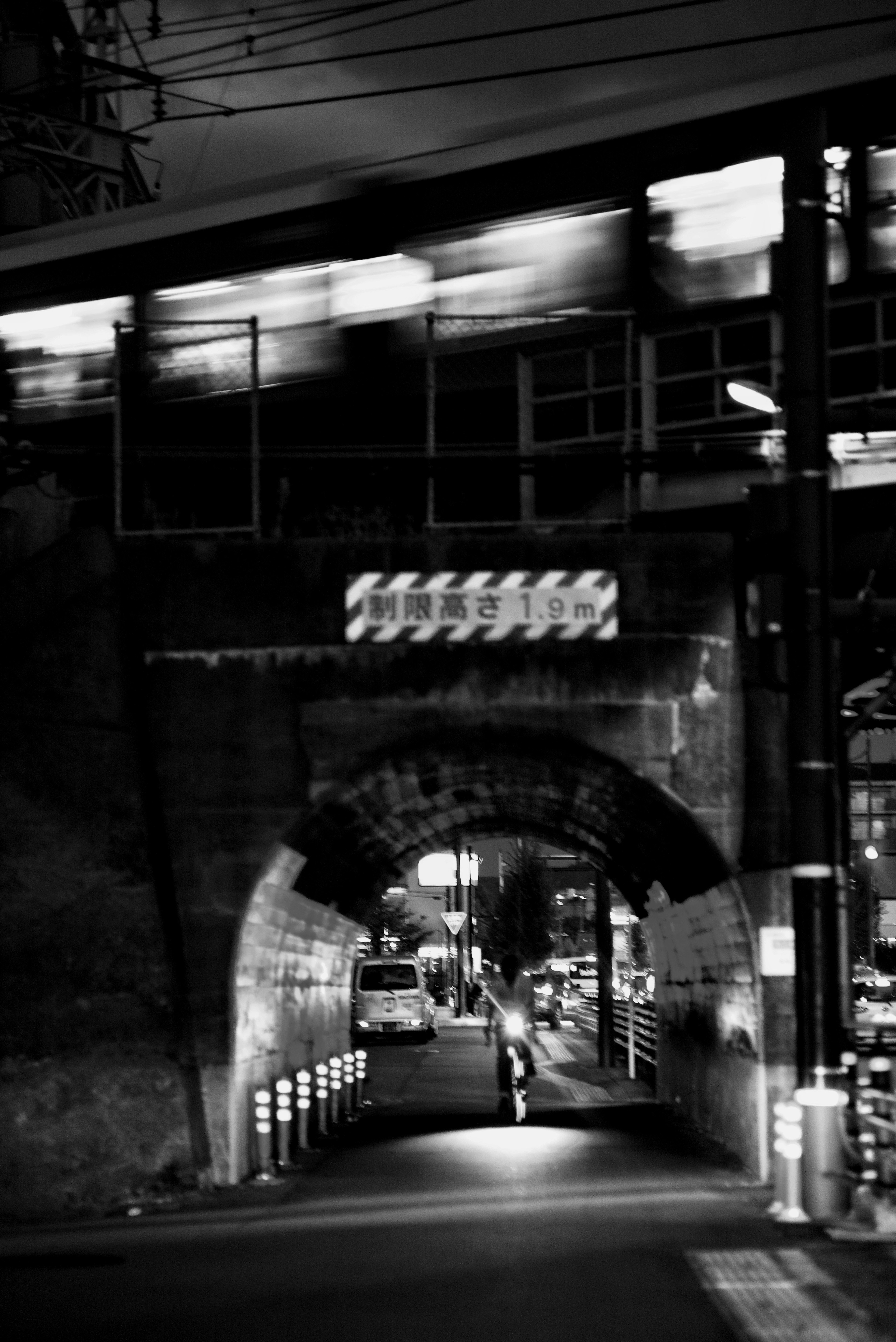 Train passing through an arch bridge in a nighttime urban setting