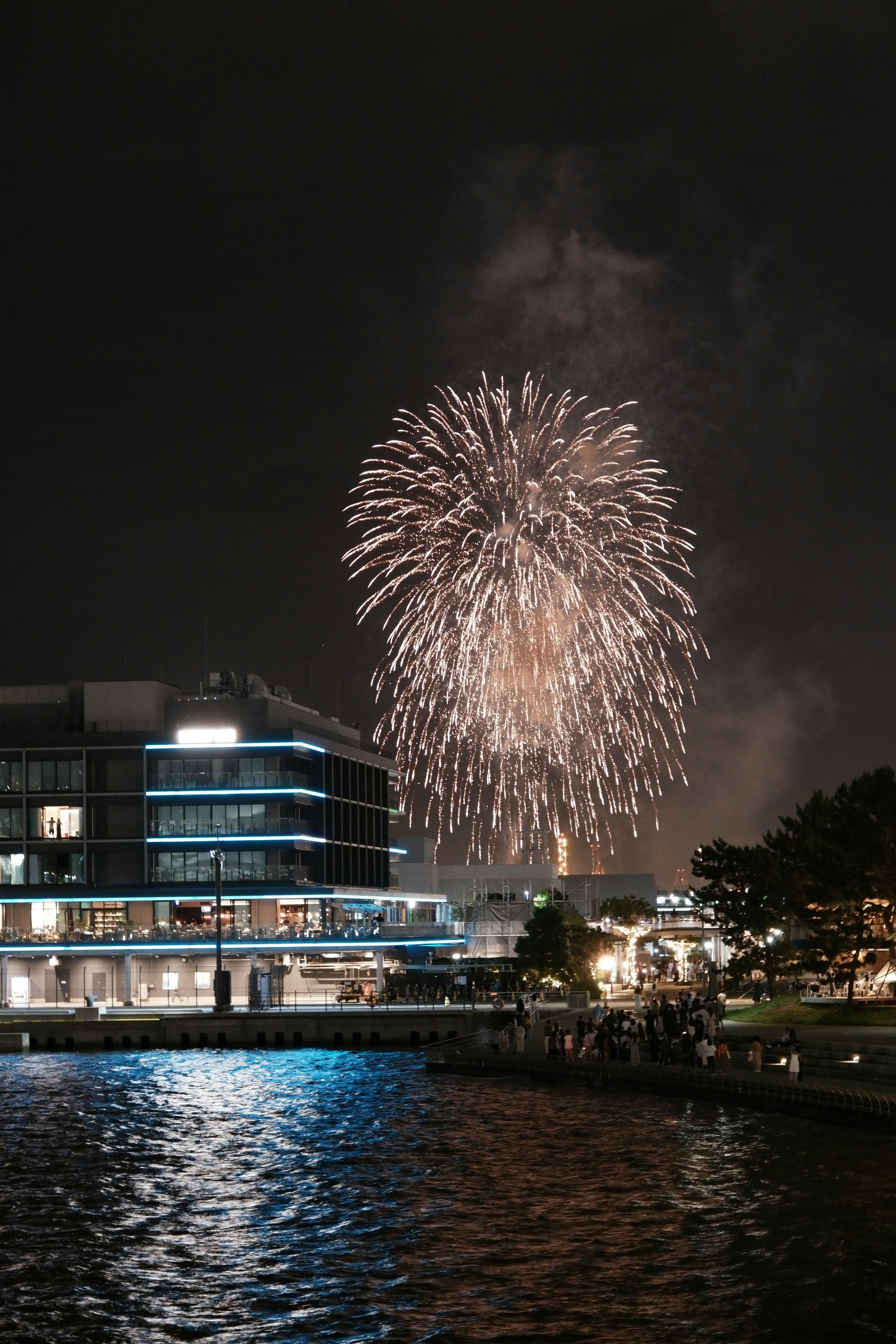 Feuerwerk erhellt den Nachthimmel über einem See mit Spiegelungen