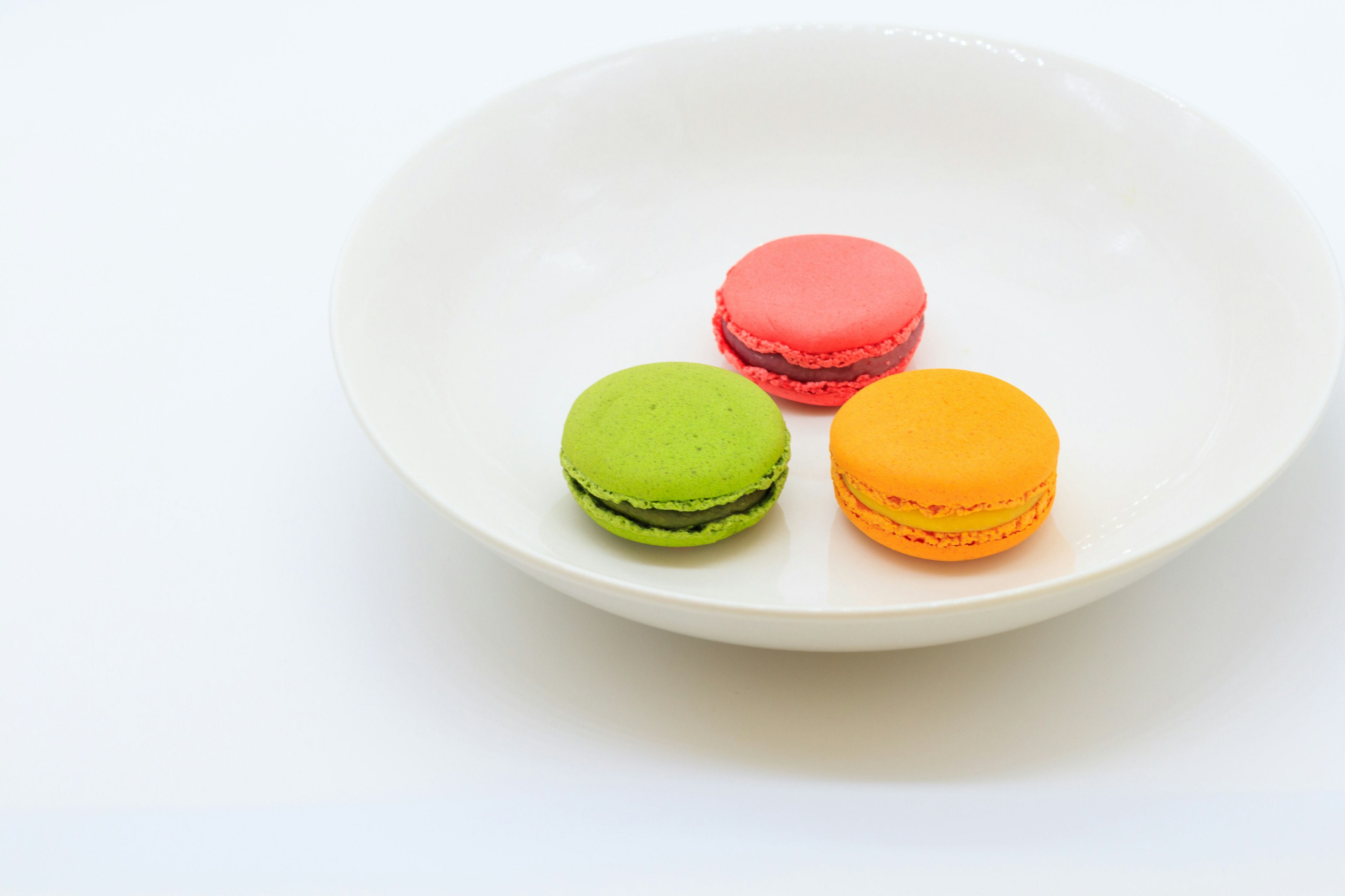 Three colorful macarons on a white plate