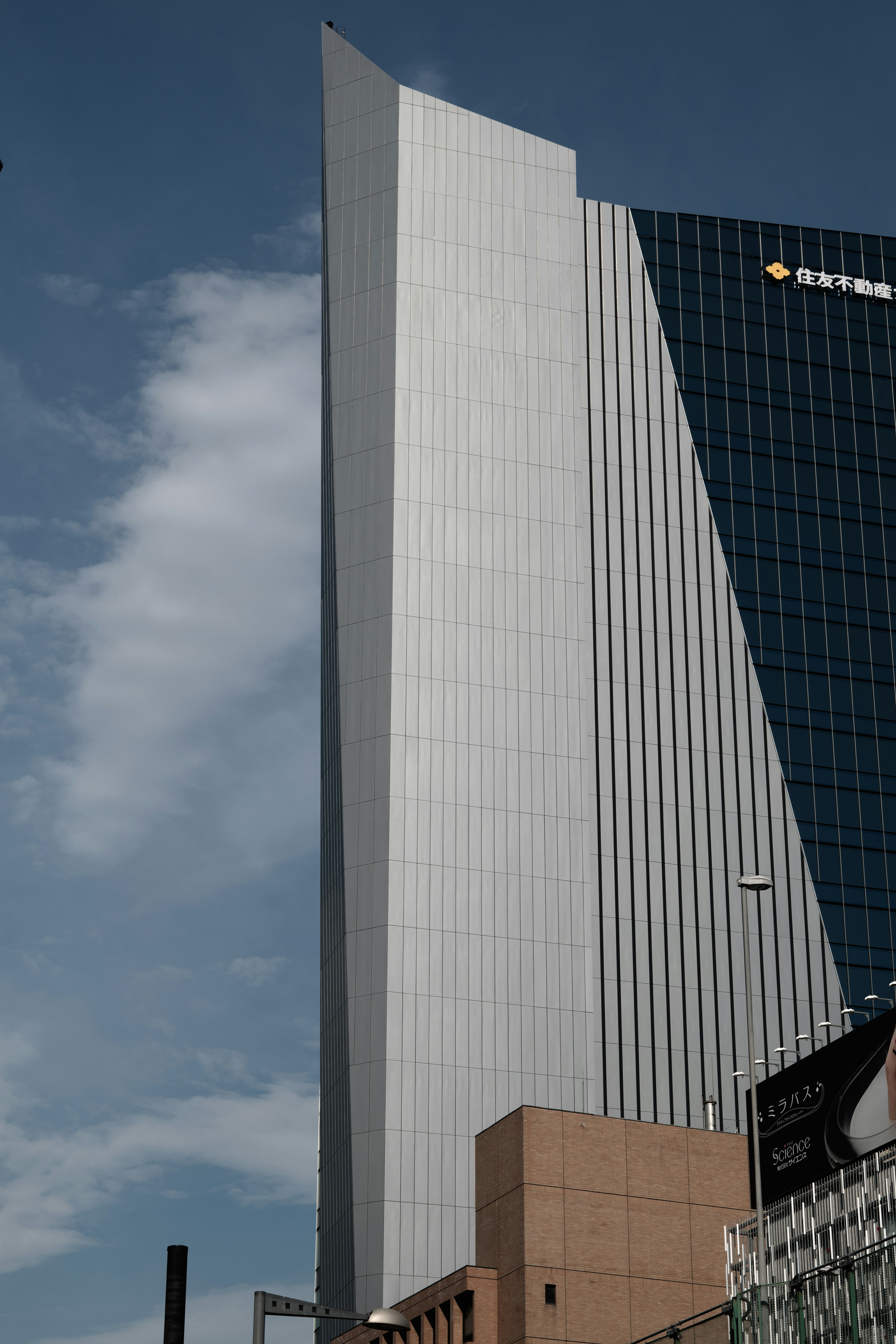 Close-up of a skyscraper featuring a triangular white roof and blue glass facade