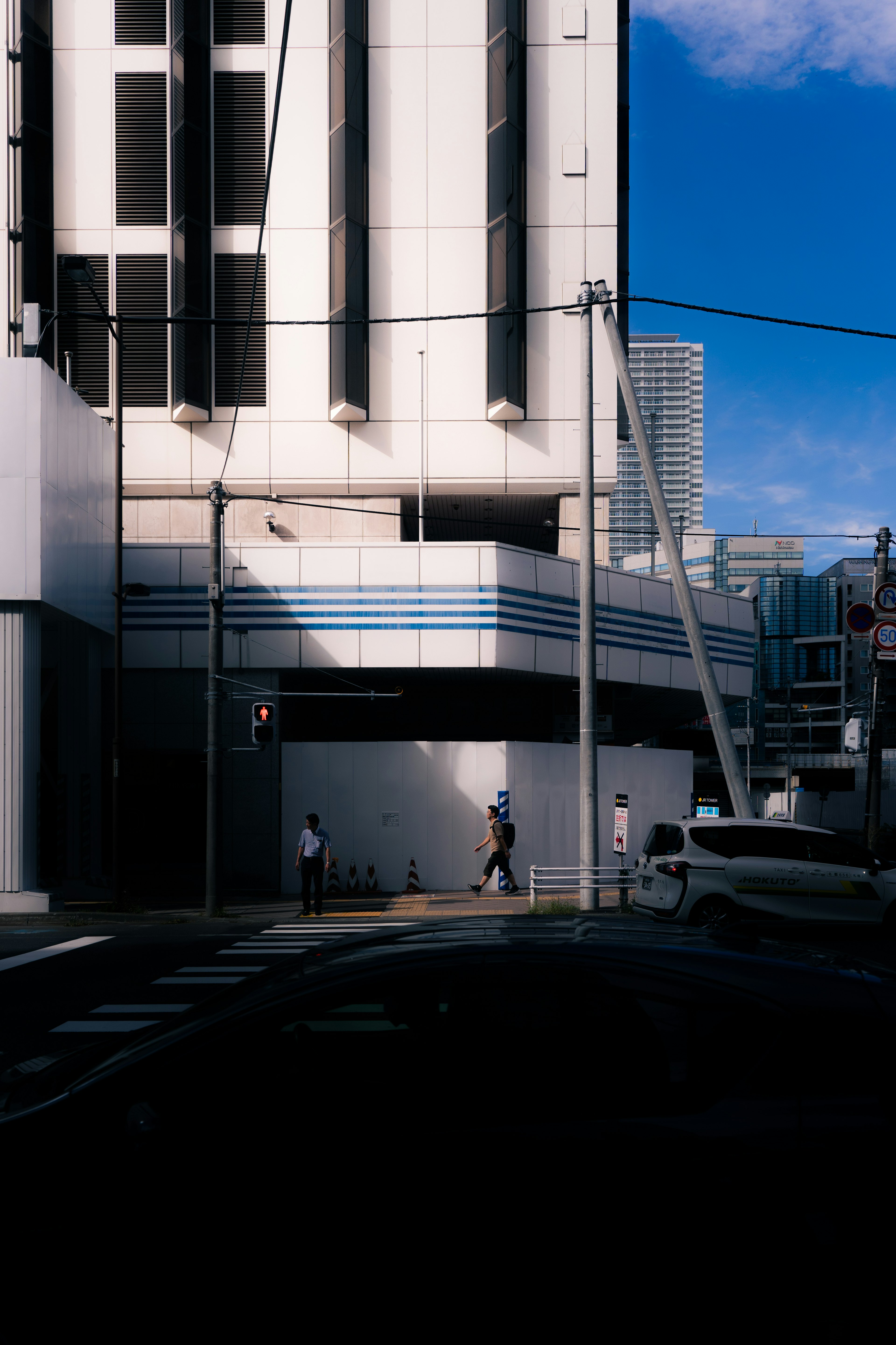 Urban scene featuring a modern building and pedestrians under a blue sky