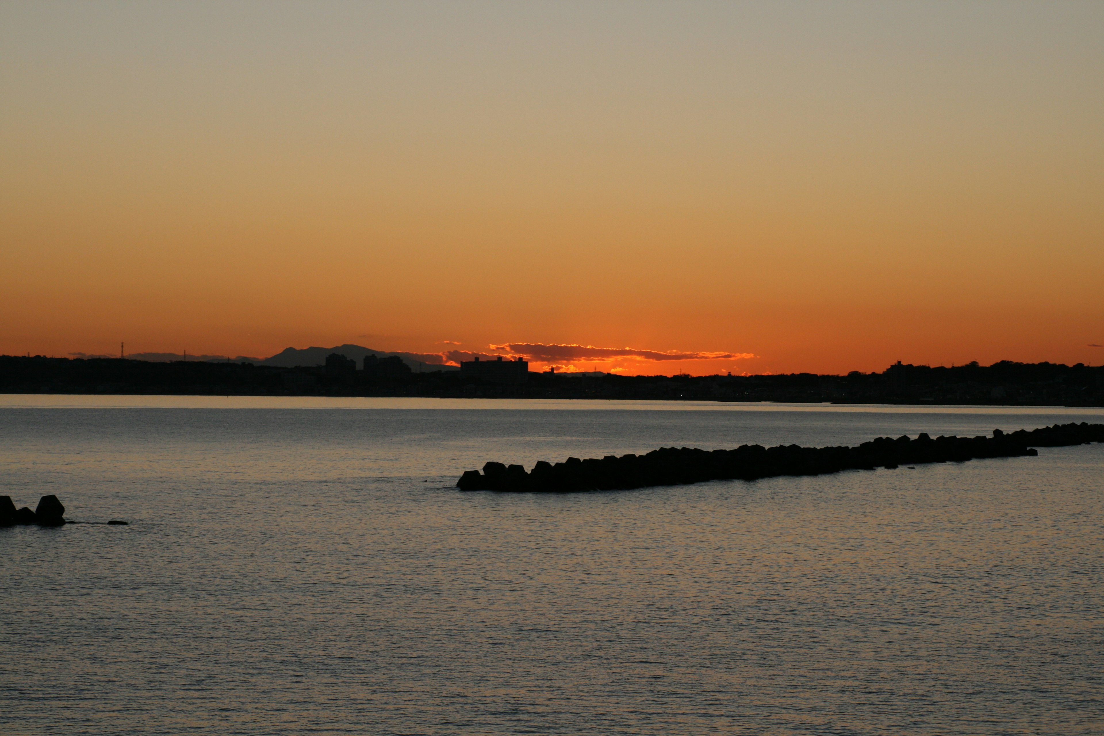 Beautiful sunset over calm waters with silhouettes of rocks