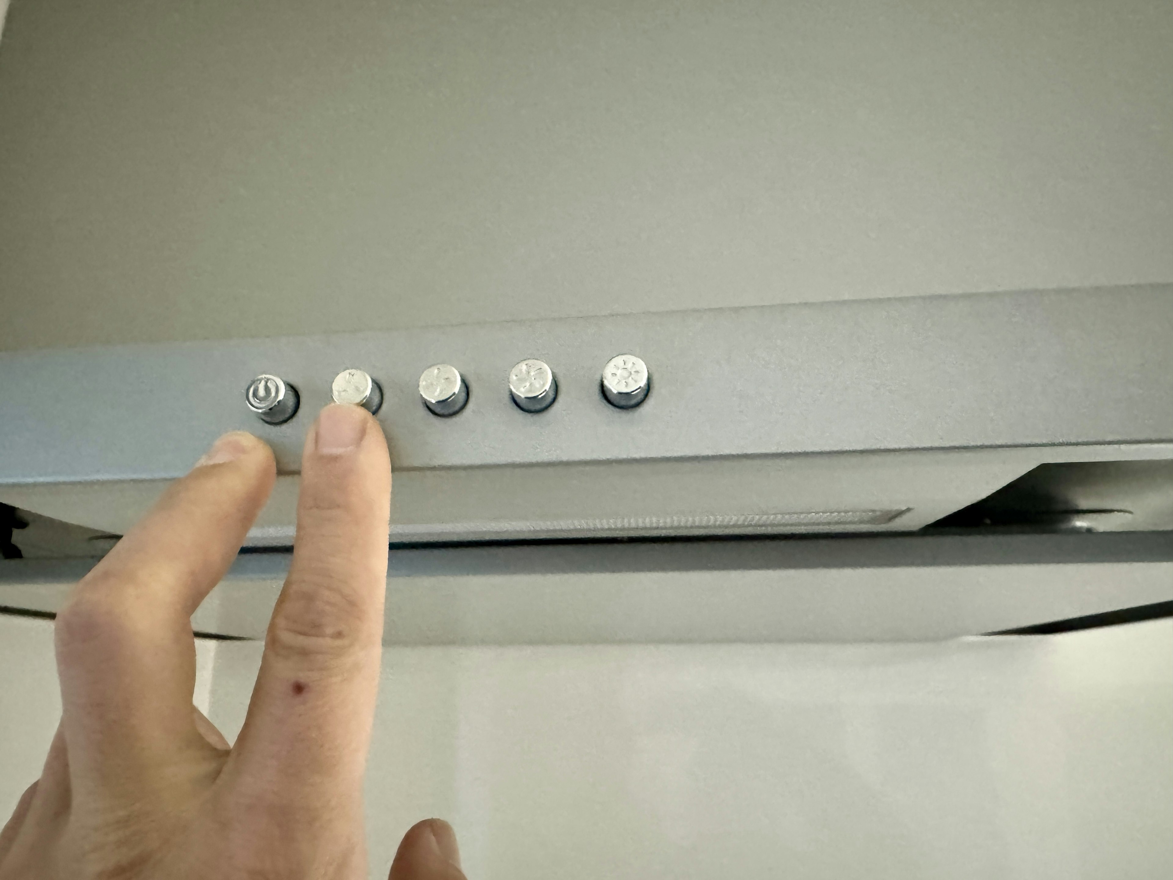 Hand pressing buttons on a kitchen range hood