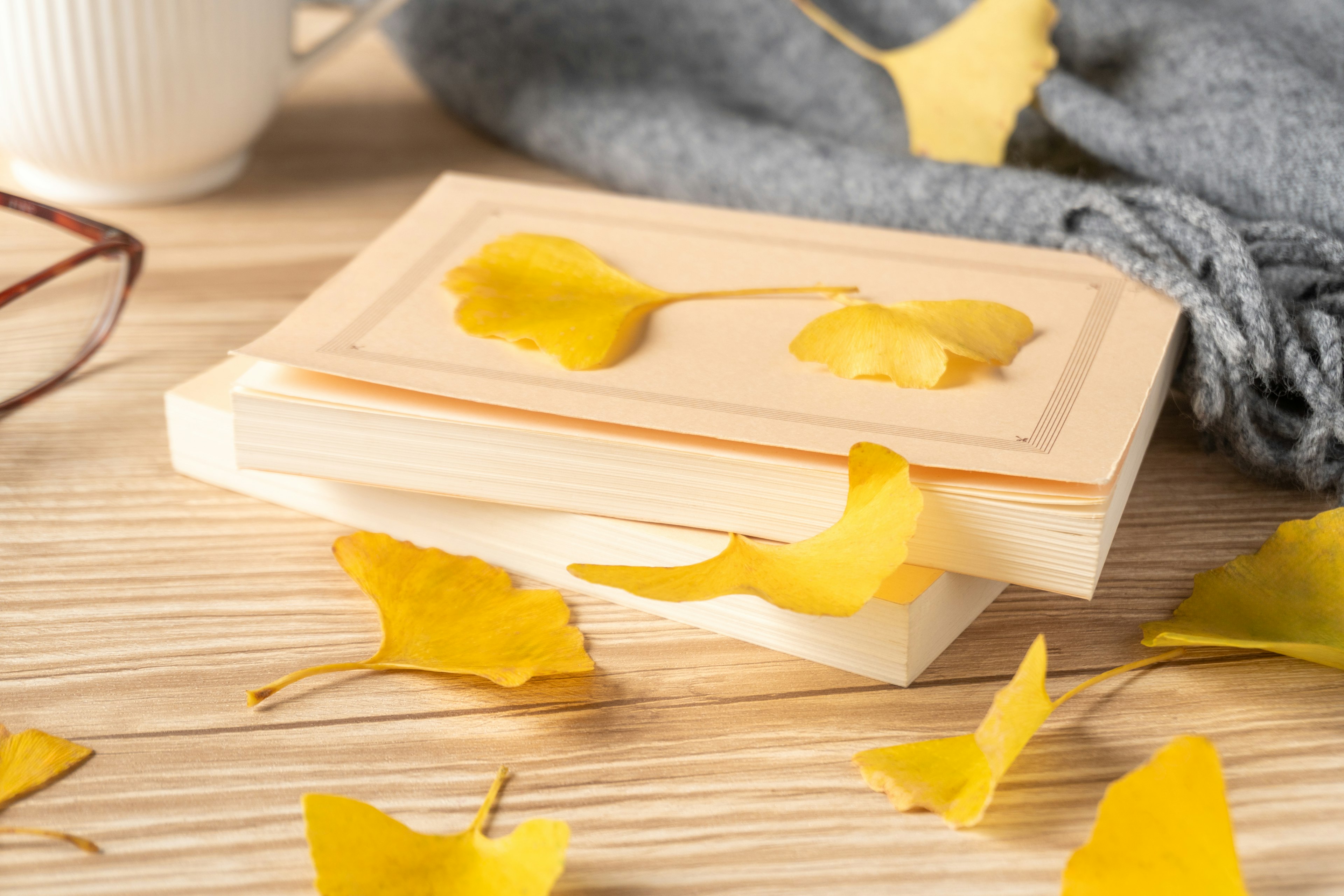 Wooden book with yellow ginkgo leaves scattered on a wooden table