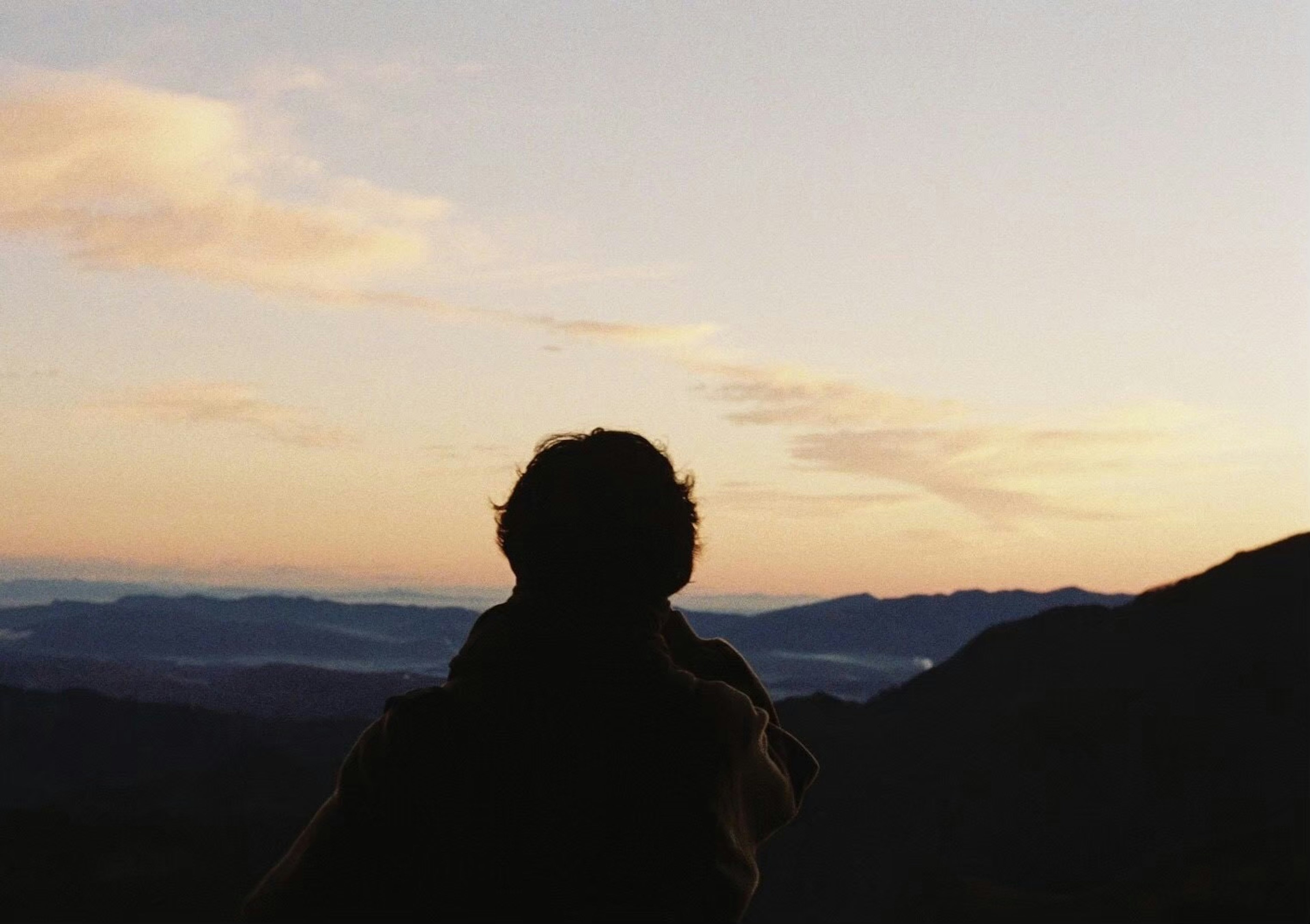 Silhouette einer Person, die eine Berglandschaft bei Sonnenuntergang betrachtet