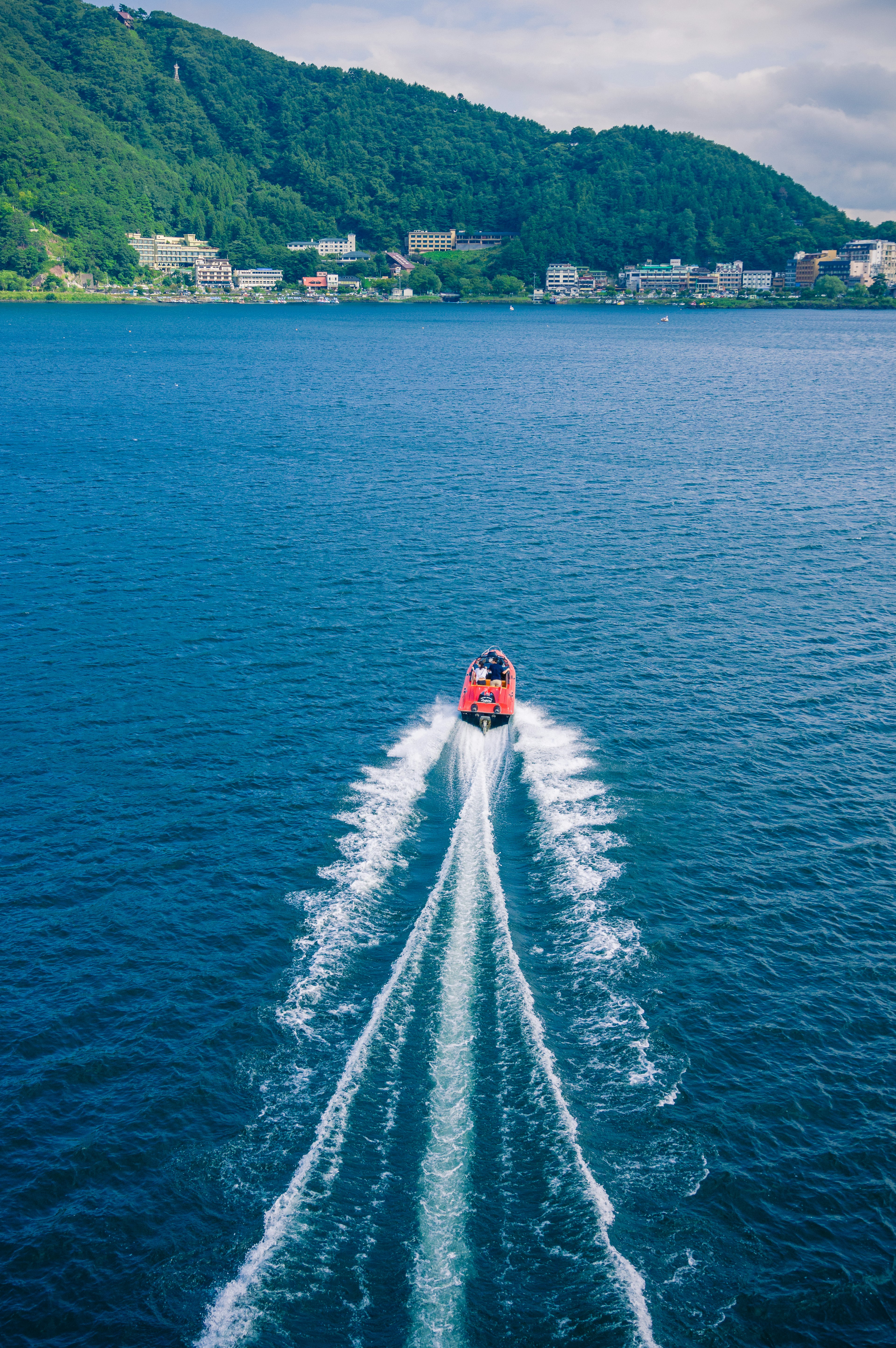 Aerial view of a red boat gliding across blue water