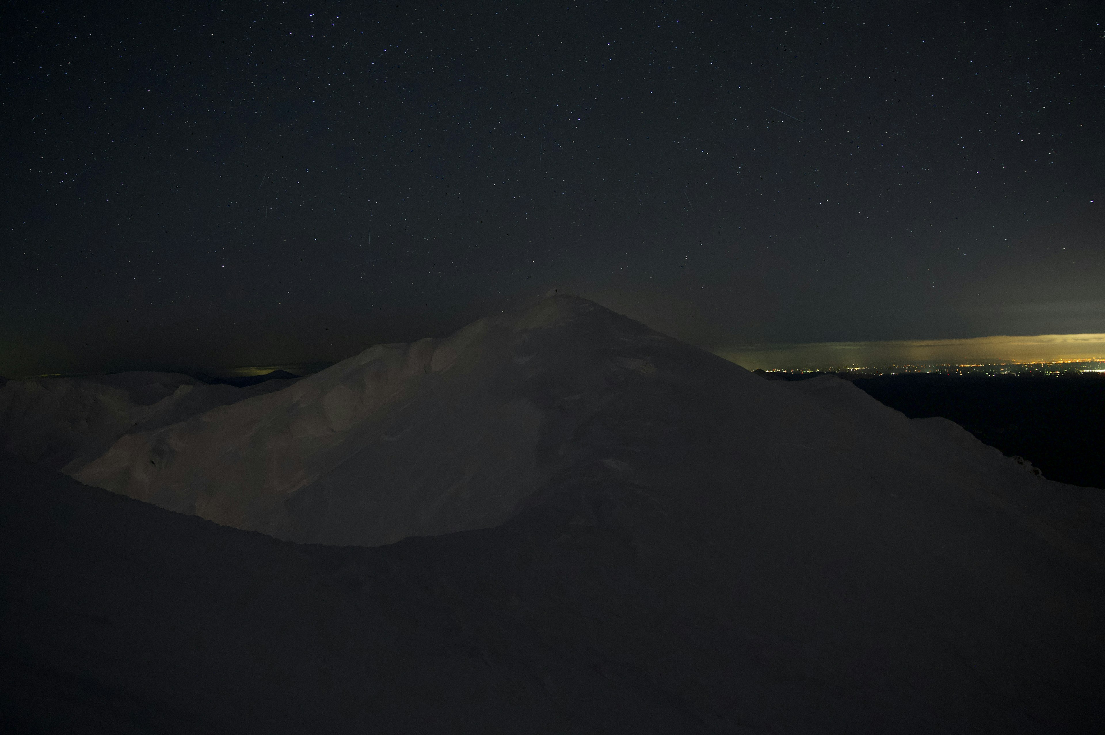 Silhouette of a snow-covered mountain under a starry sky