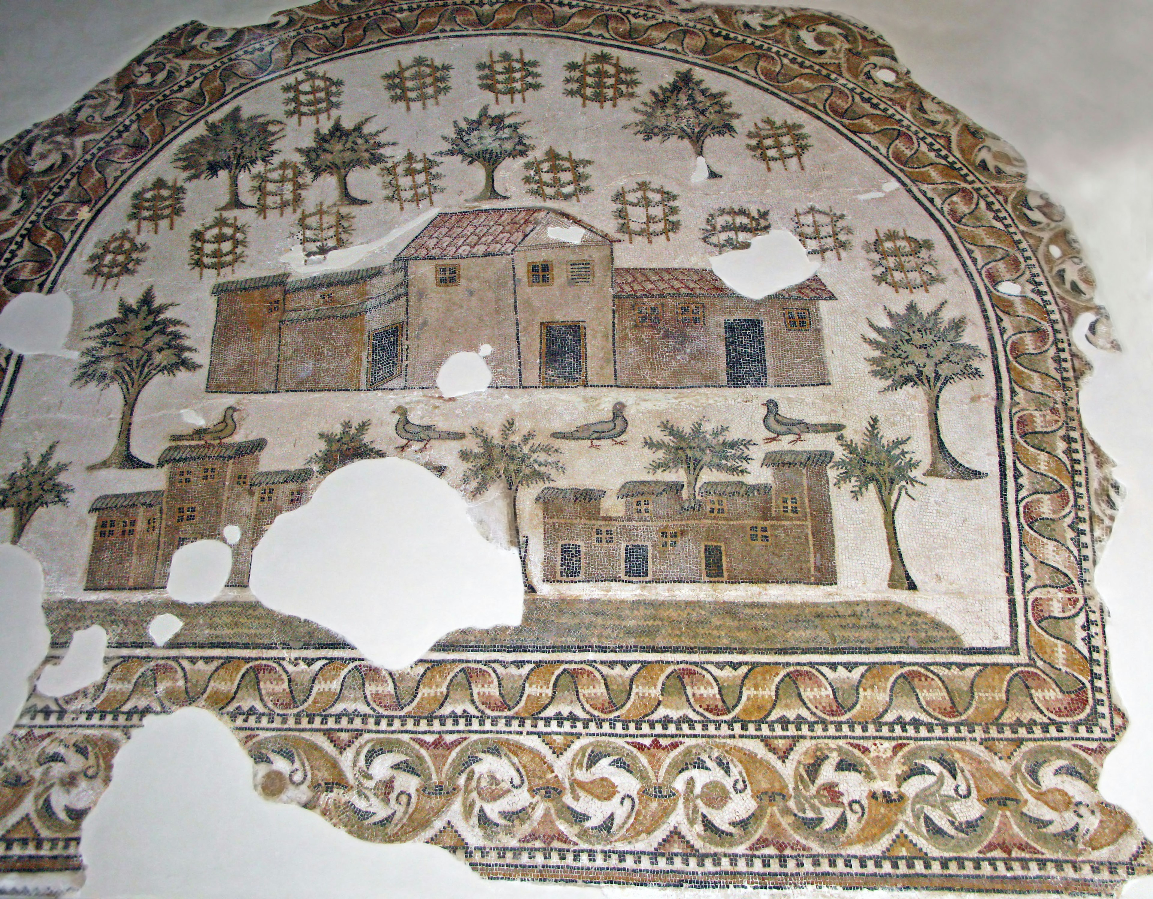 Ancient mosaic art depicting houses and trees with some damage