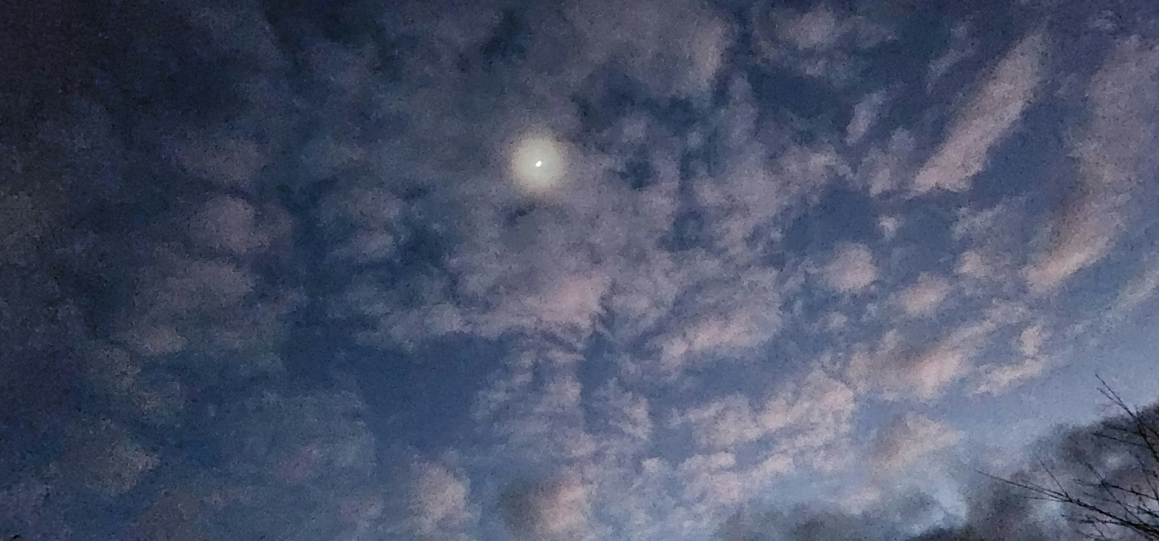 A scenic view of a blue sky filled with clouds and a glowing moon