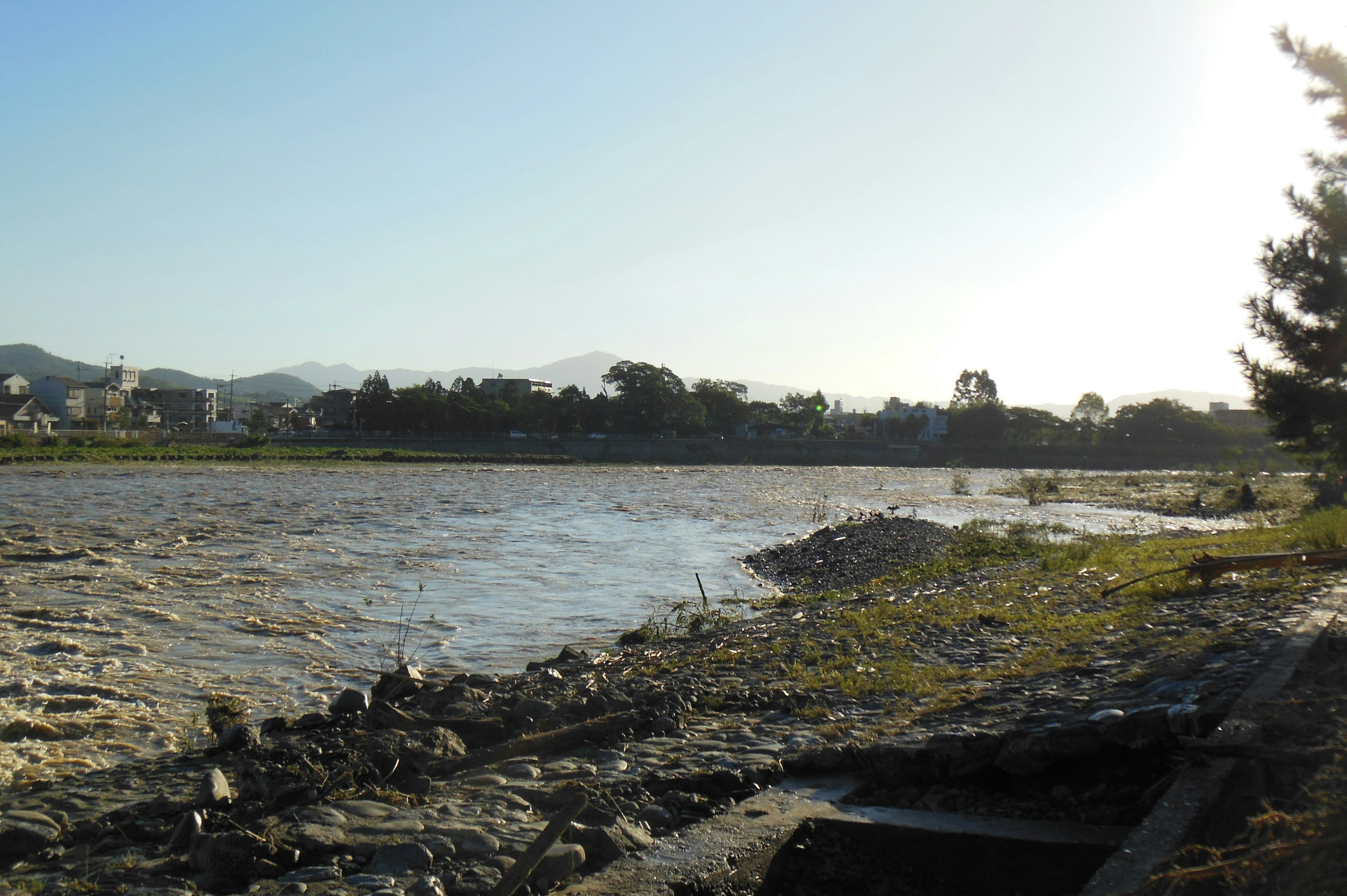 Pemandangan sungai tenang dengan pegunungan di latar belakang