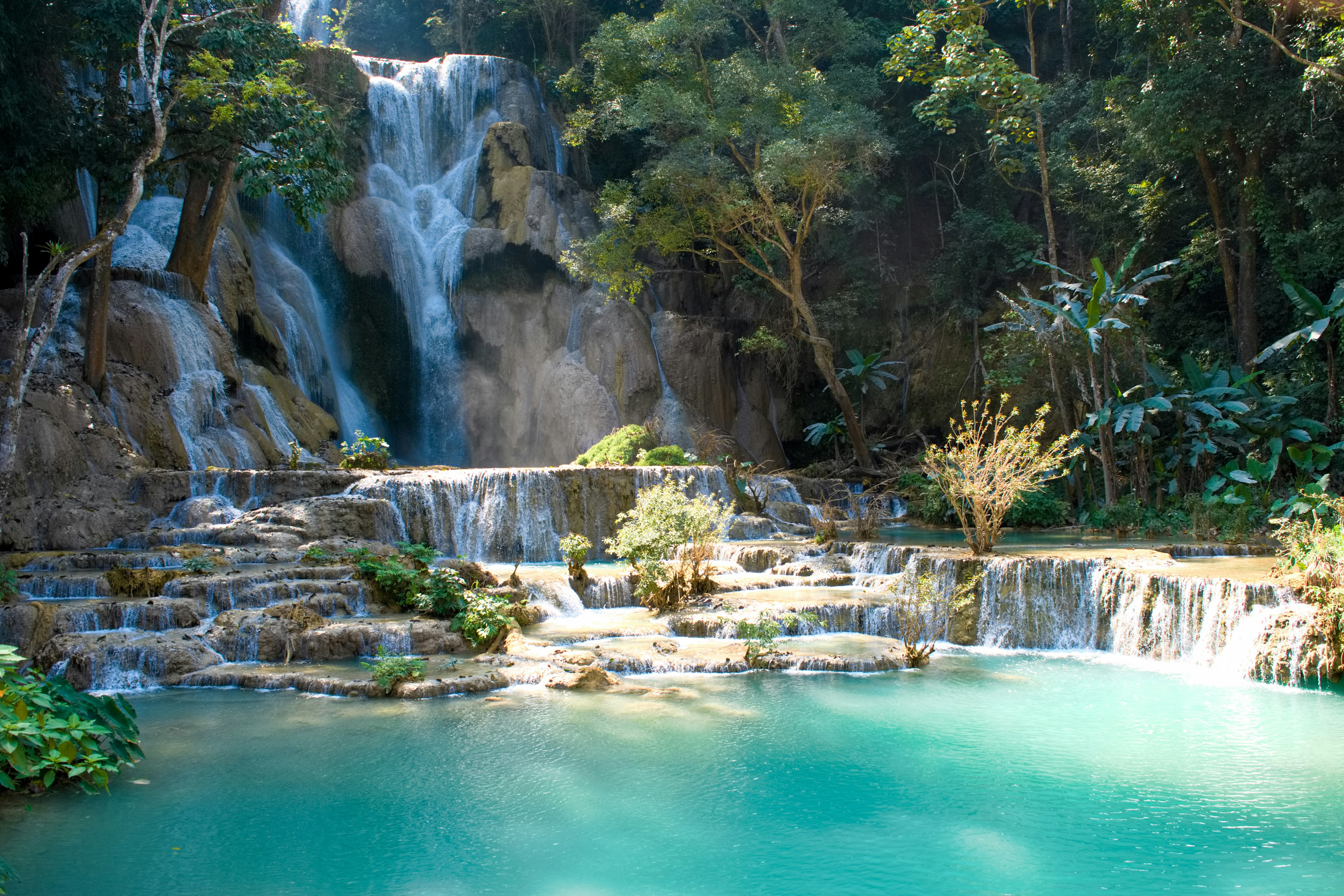 Air terjun yang indah dengan kolam berwarna turquoise dikelilingi oleh pepohonan lebat