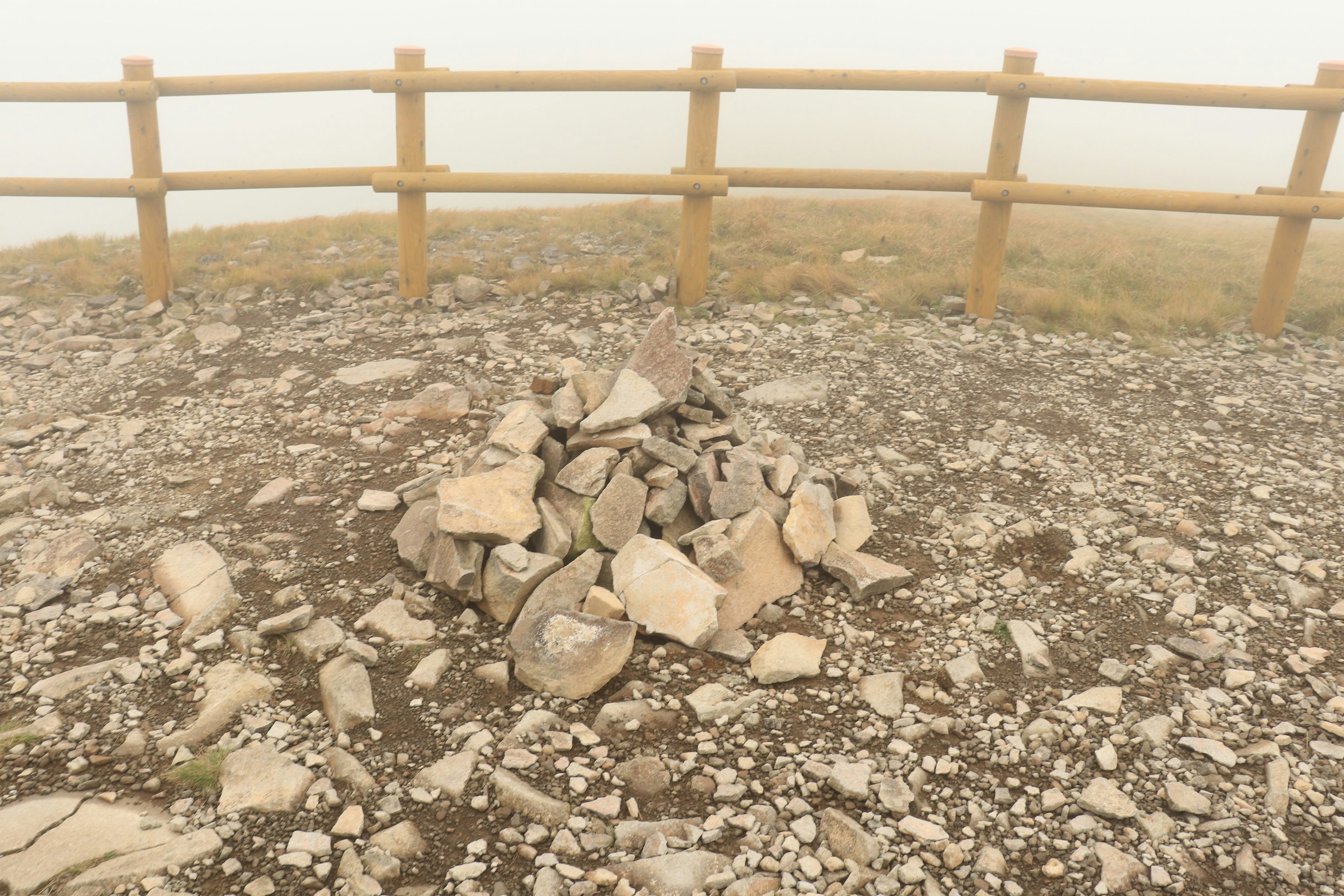 Montón de piedras en la niebla con cerca de madera