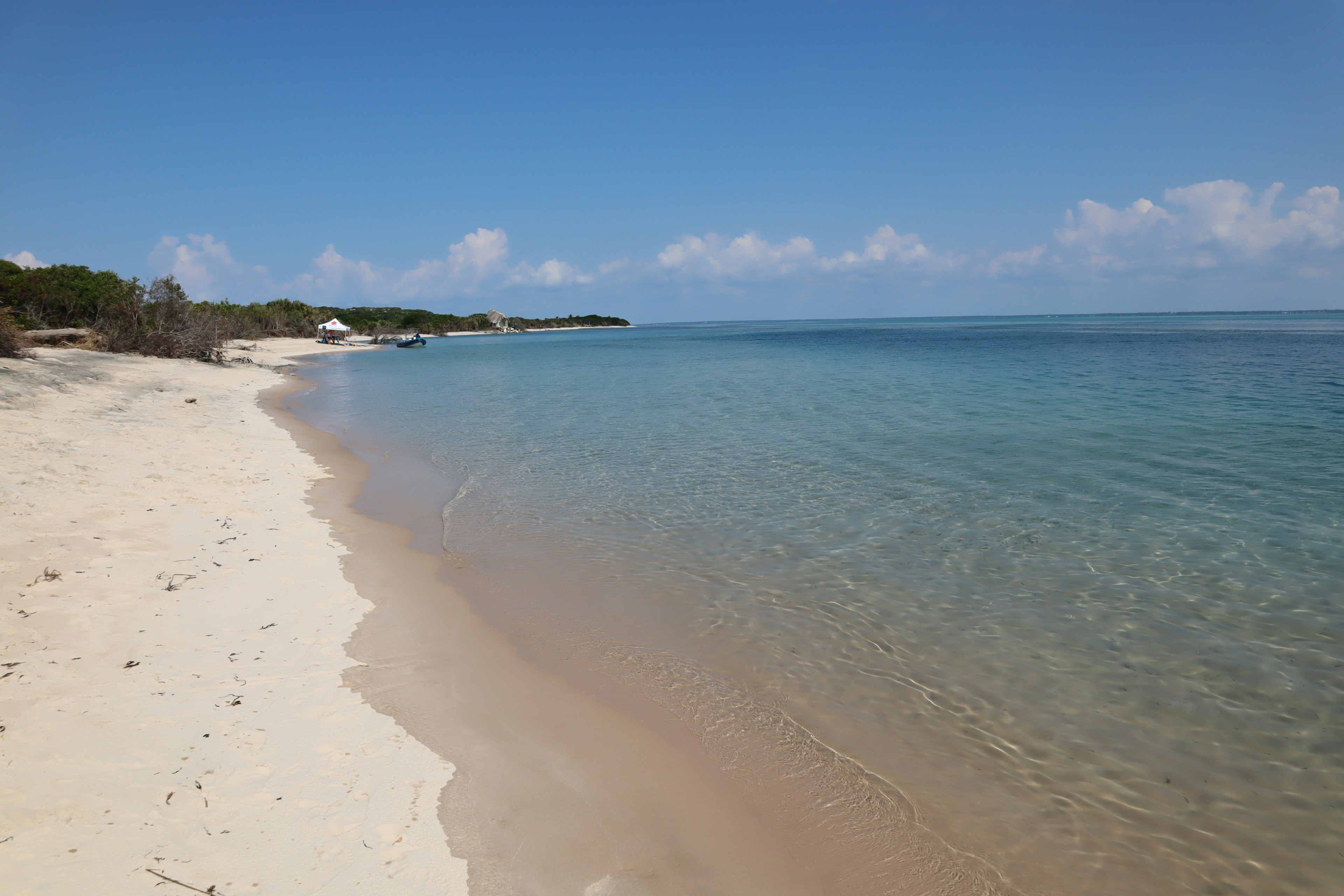 ชายหาดกับน้ำทะเลสีฟ้าสดใสและชายฝั่งทราย