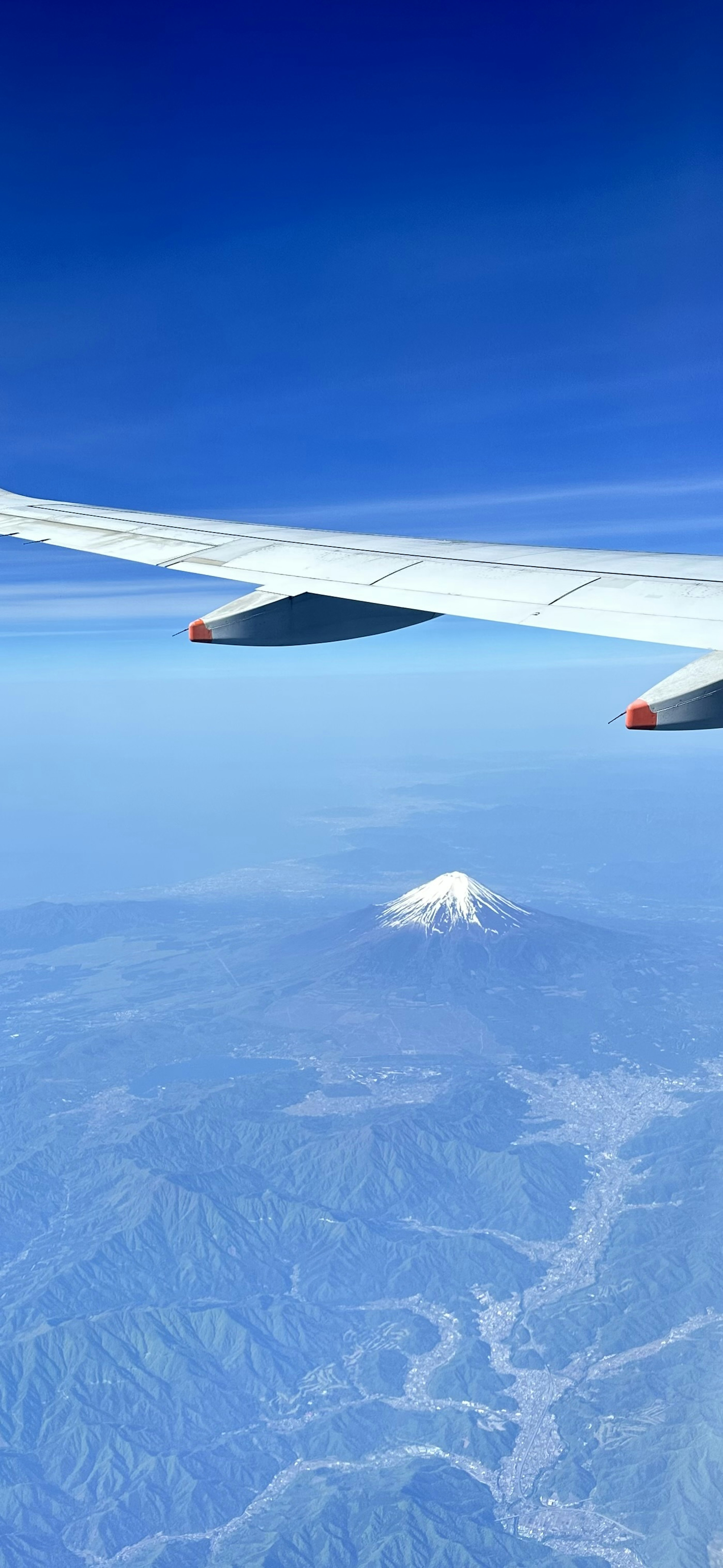 飛行機の翼と背景の青い空と山