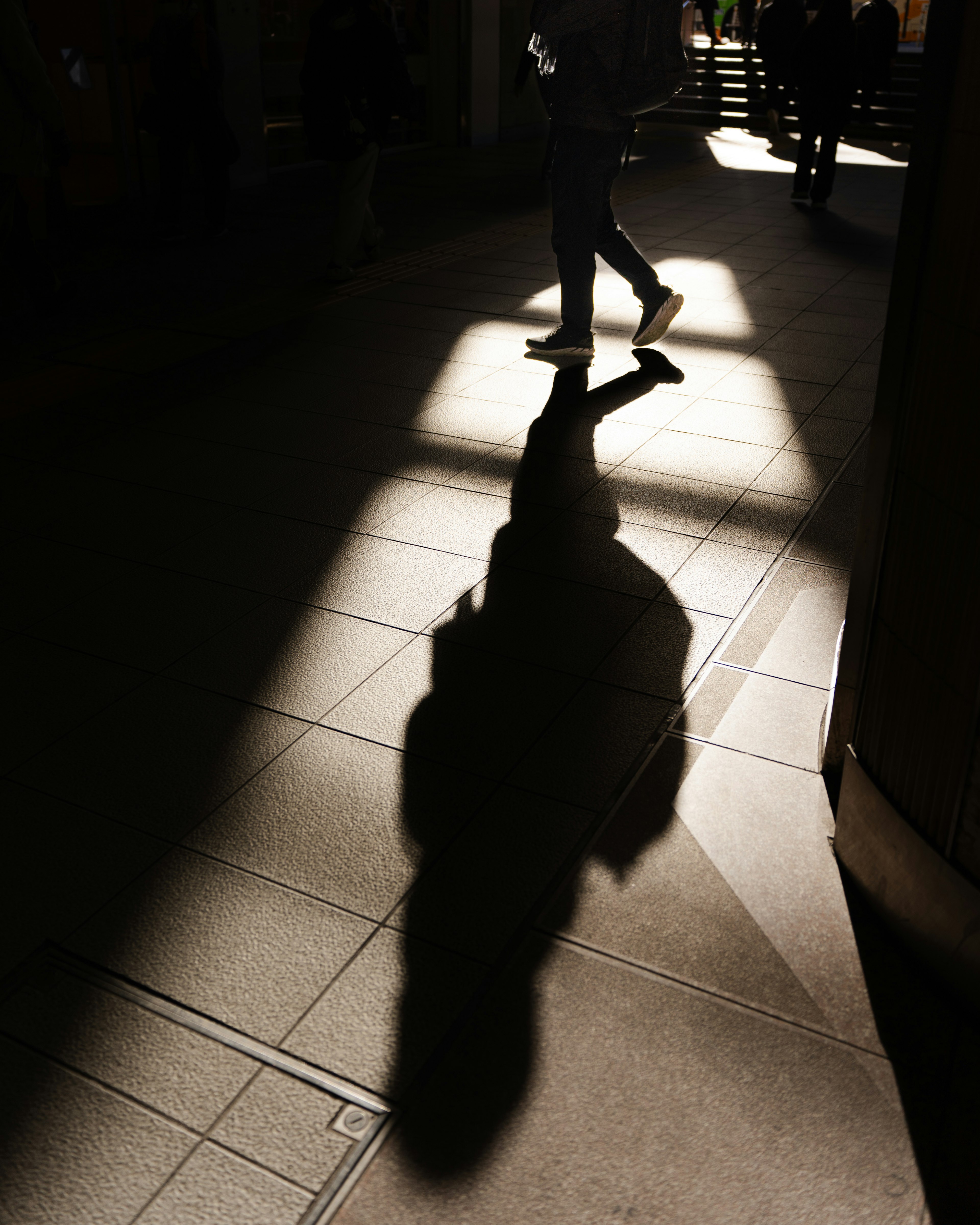 Una persona che cammina per strada proiettando un'ombra lunga