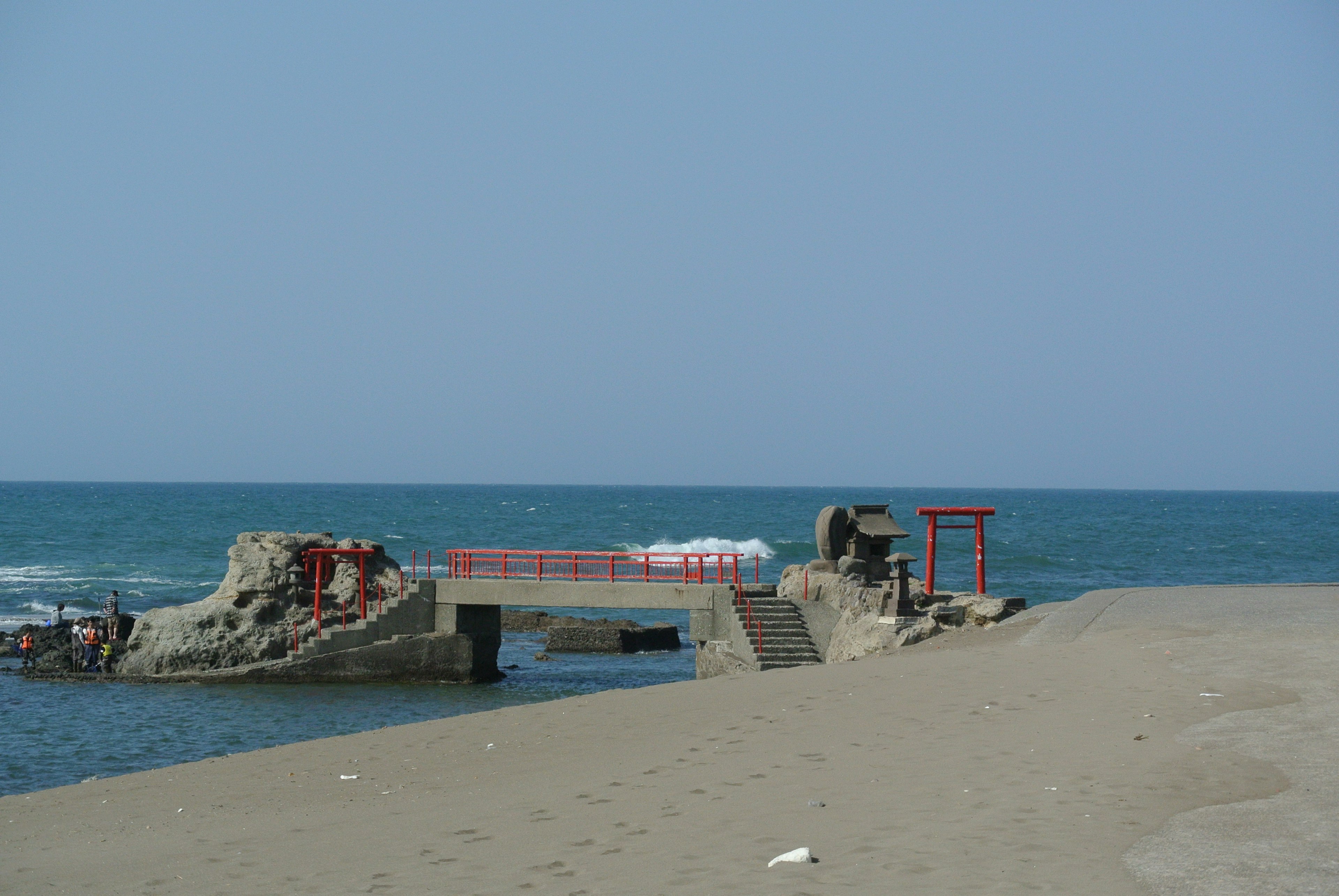 海岸にある赤い鳥居と崩れた桟橋の風景