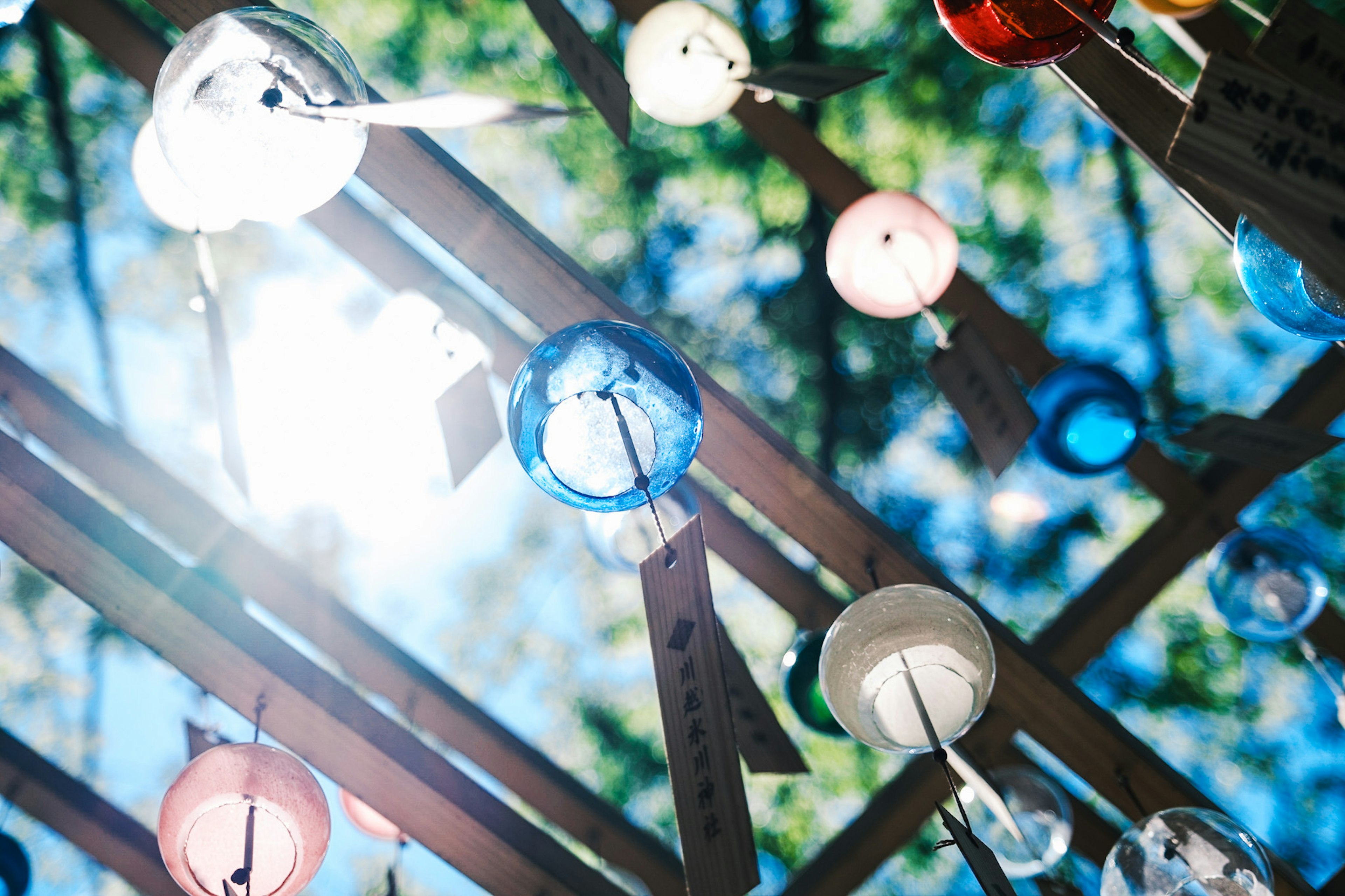 Carillons colorés en bleu, rouge et blanc suspendus au-dessus avec la lumière du soleil qui filtre