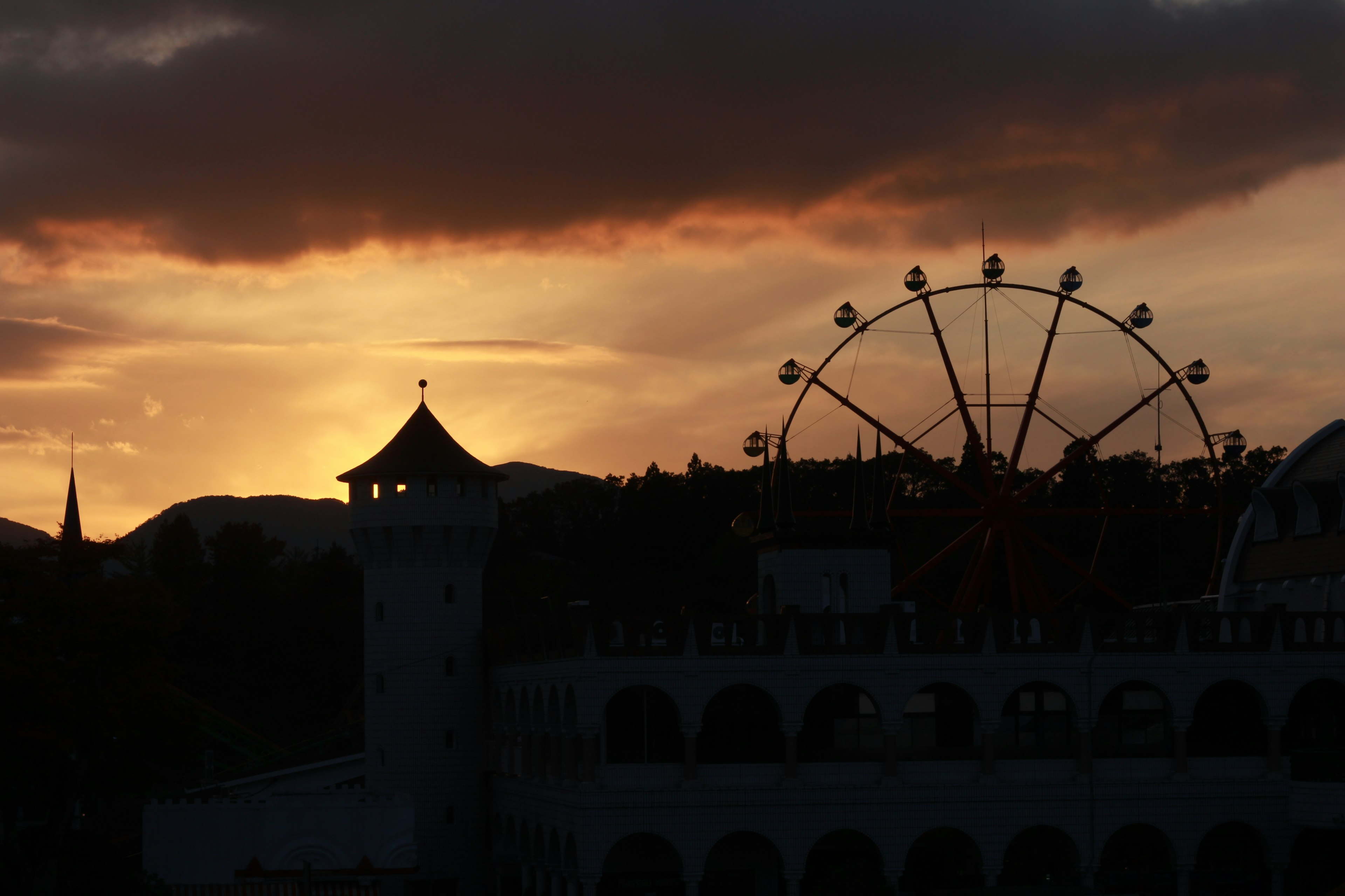 Silhouette d'une grande roue et d'une tour contre un ciel de coucher de soleil