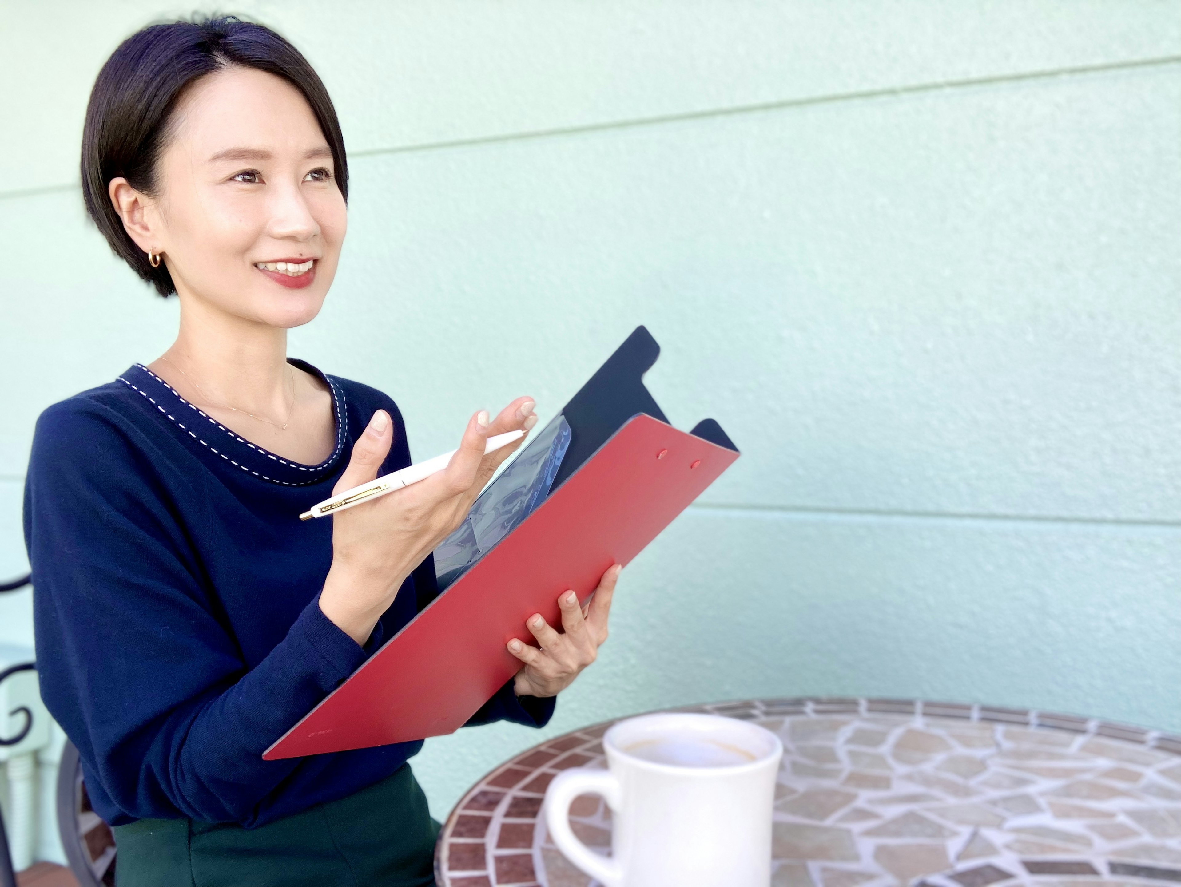 Mujer sonriendo mientras sostiene una carpeta roja y habla