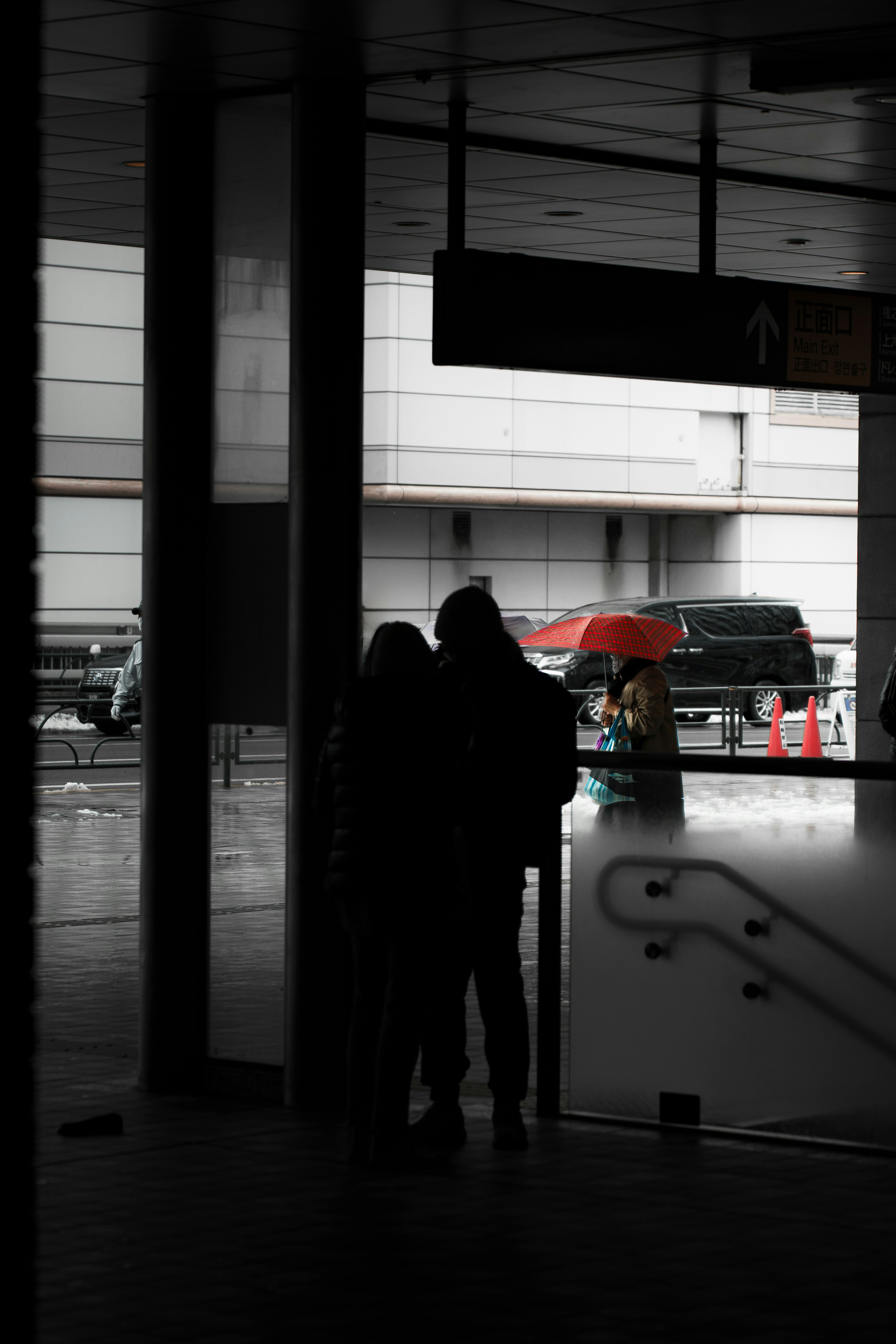 二人のシルエットがガラスの前に立っている雨の日の都市風景