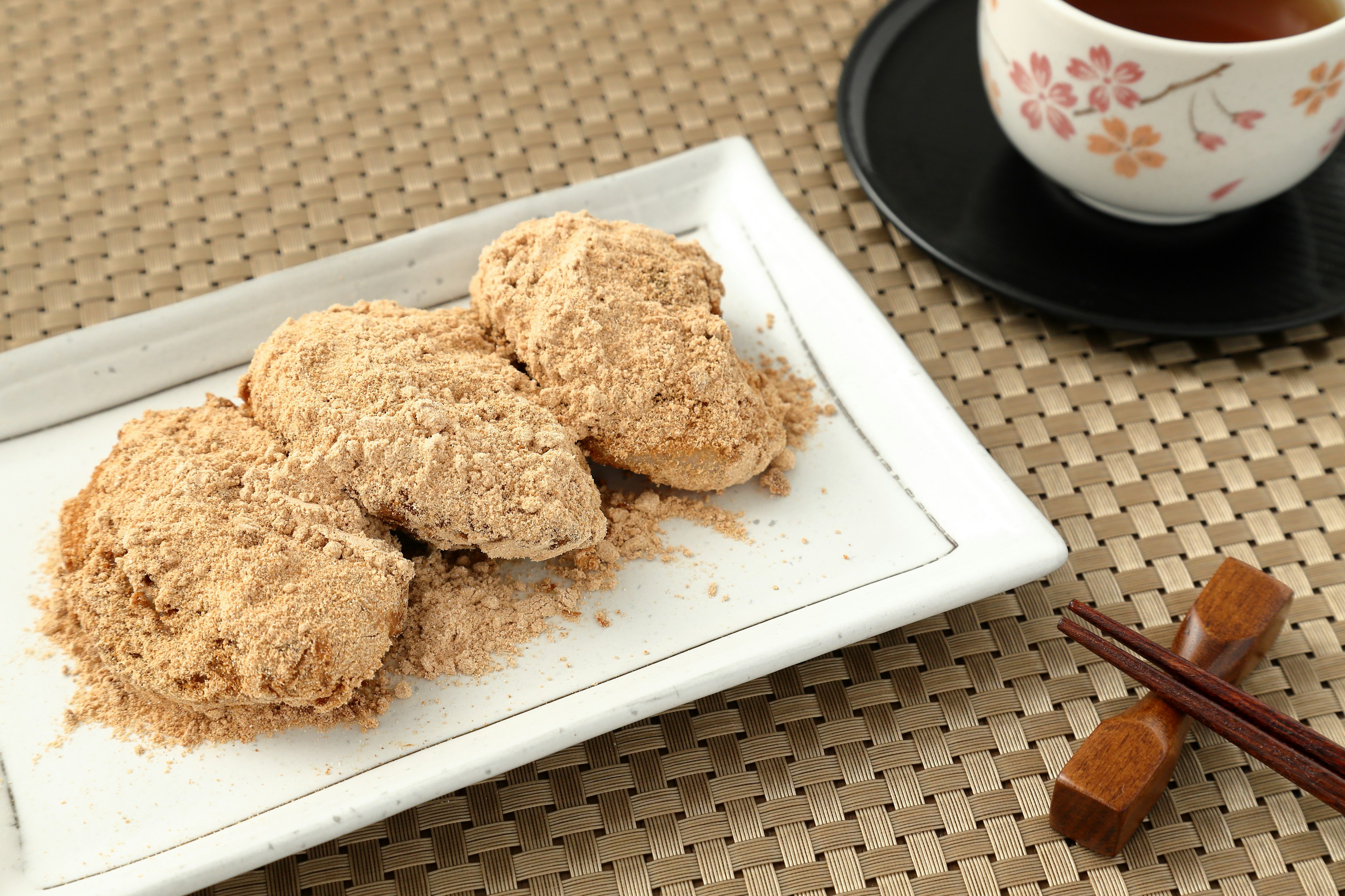 Plate of sweet rice cakes covered in soybean flour with tea