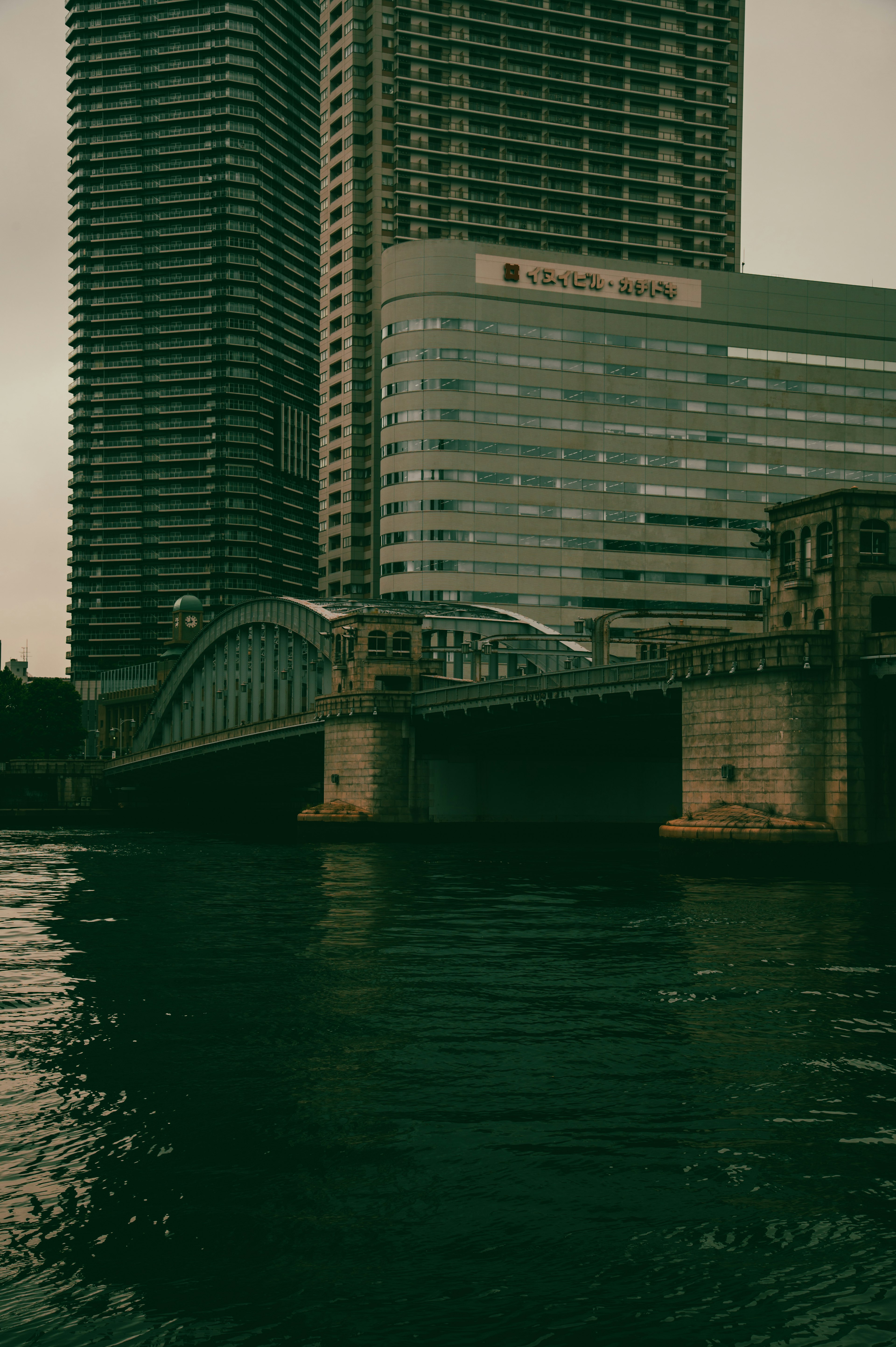 Cityscape featuring a high-rise building and a bridge reflected in the water