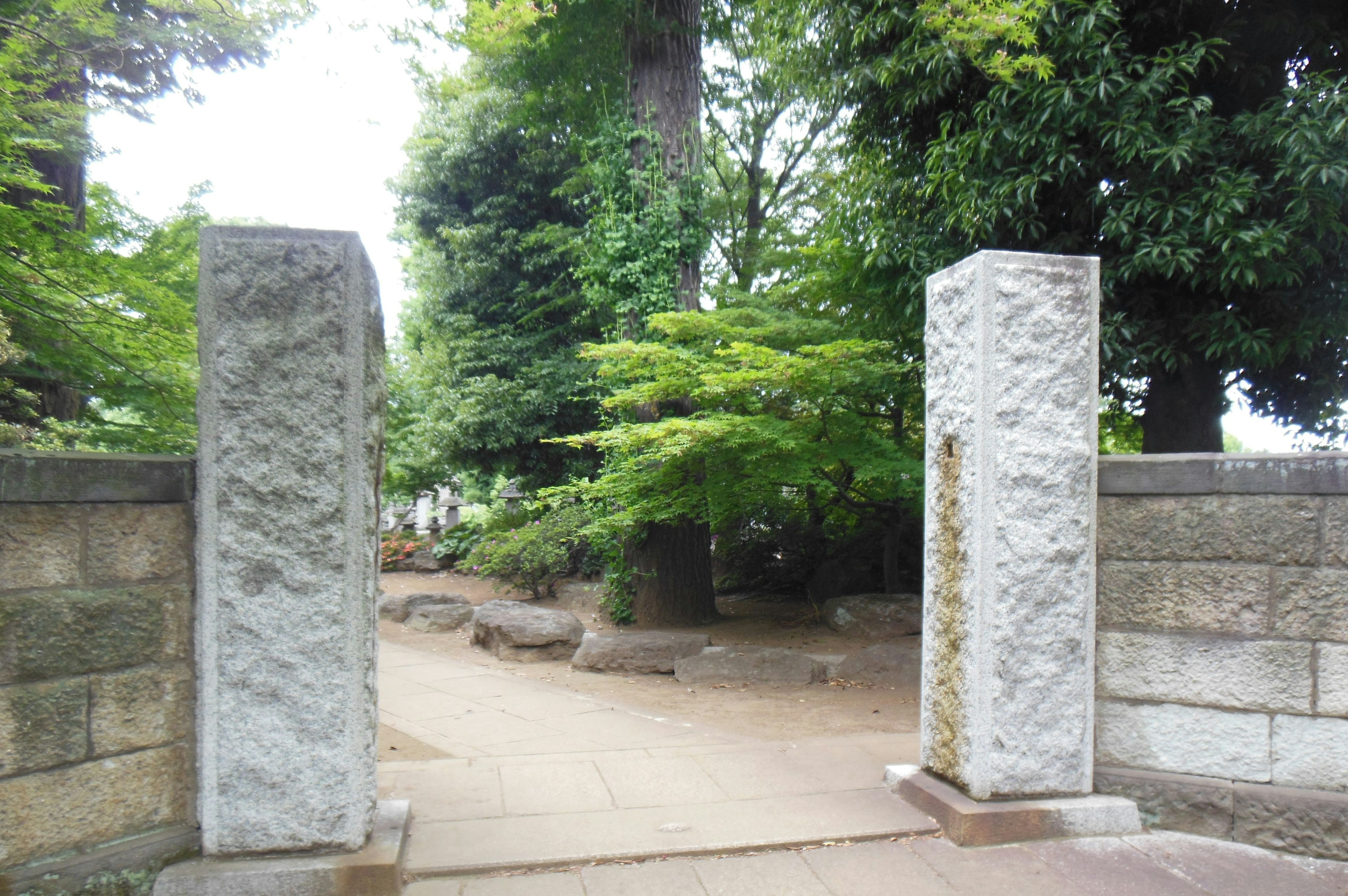 Porte en pierre menant à un jardin luxuriant avec de la verdure