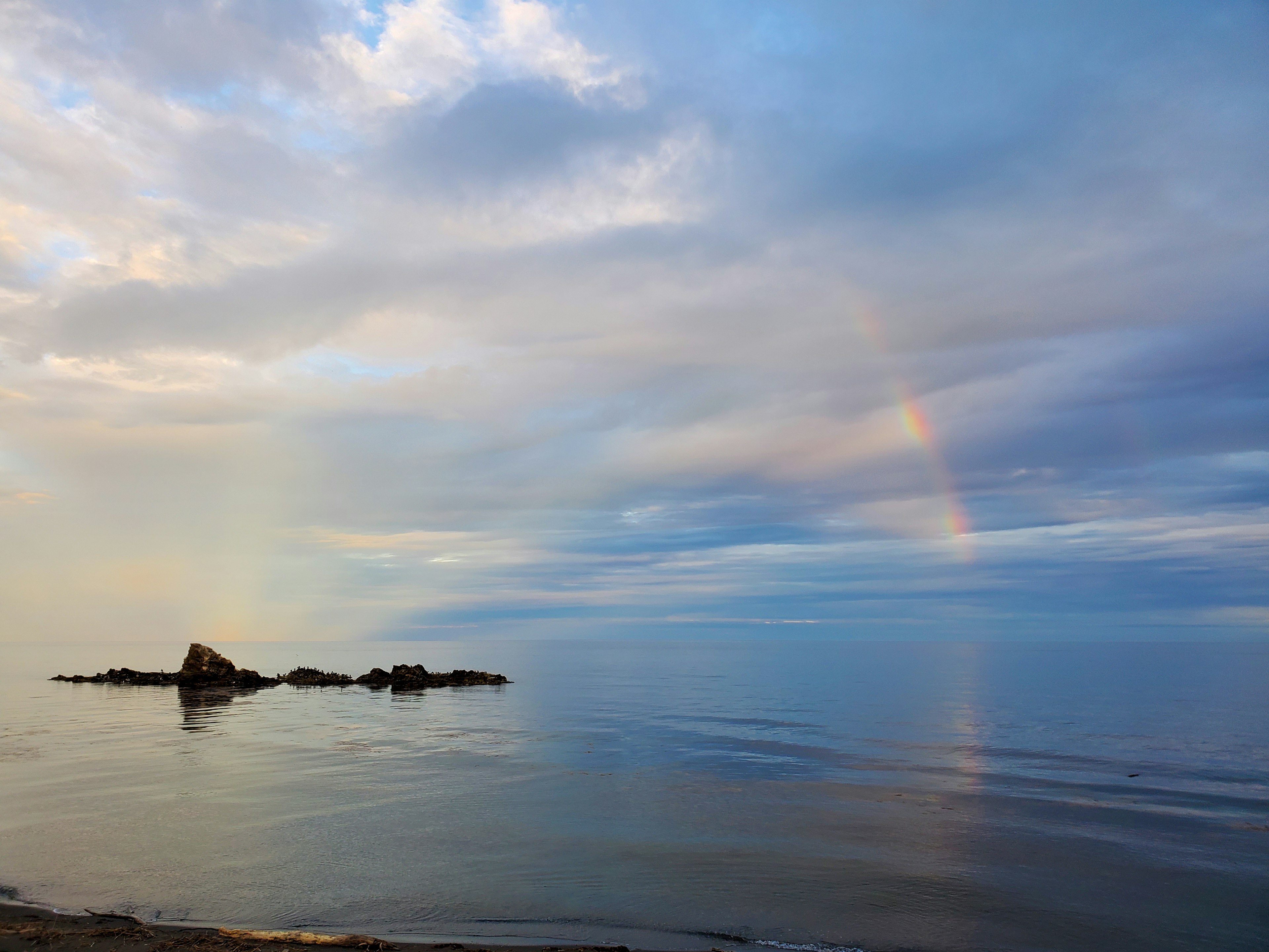 Mare calma con un arcobaleno nel cielo