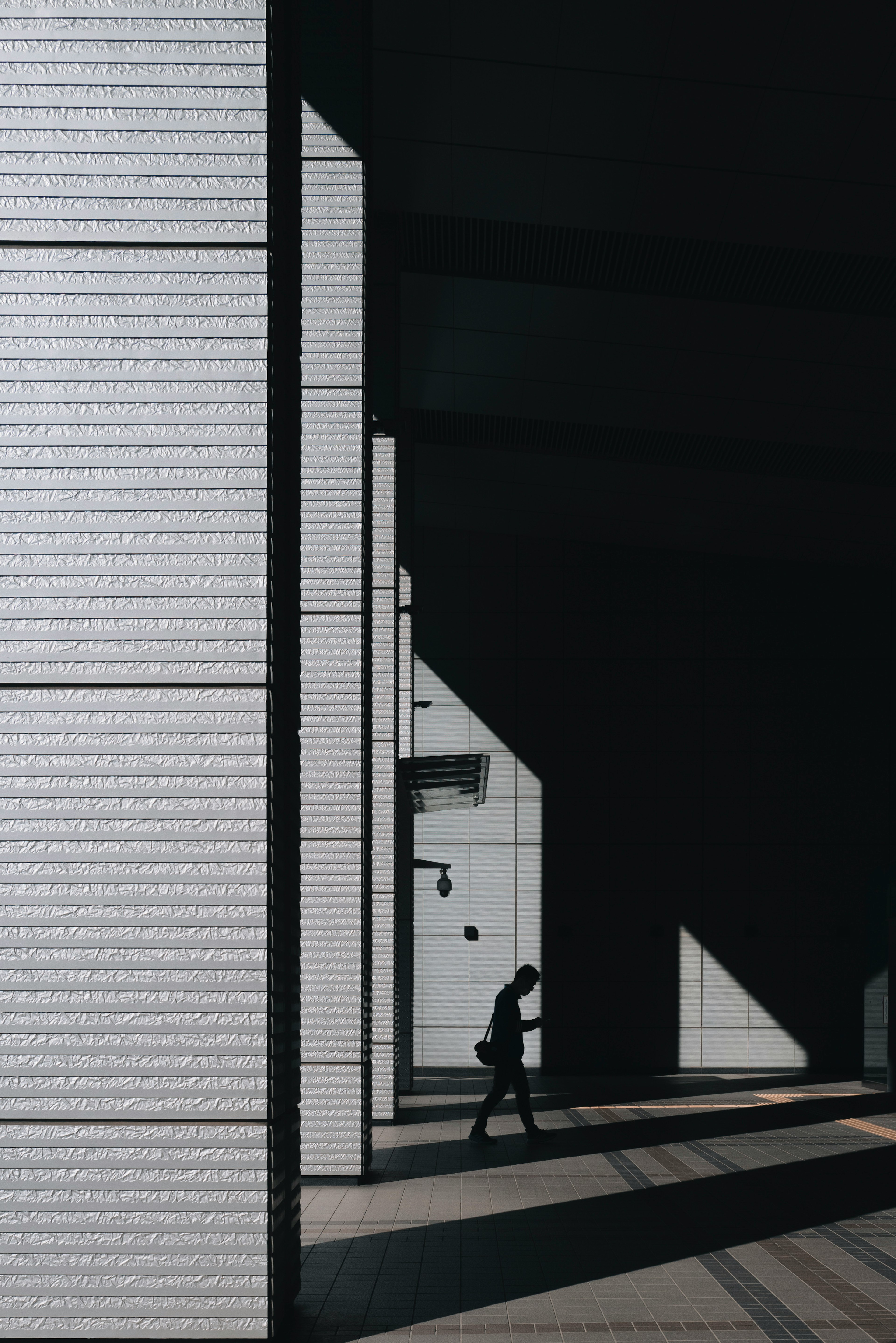 Una figura caminando a través de estructuras arquitectónicas modernas en sombras