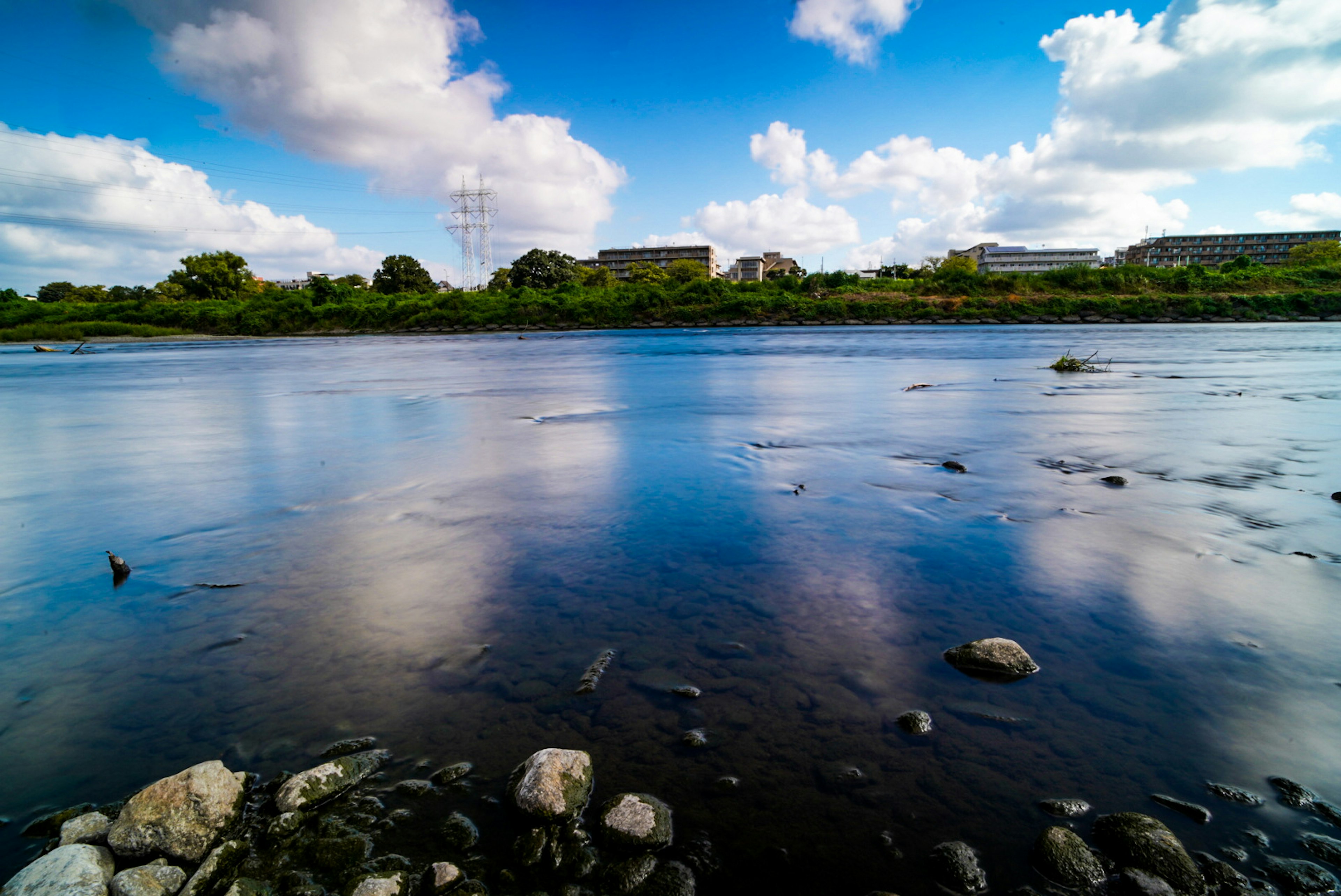 Malersches Flusslandschaft mit Reflexionen des blauen Himmels und Wolken felsiger Uferbereich