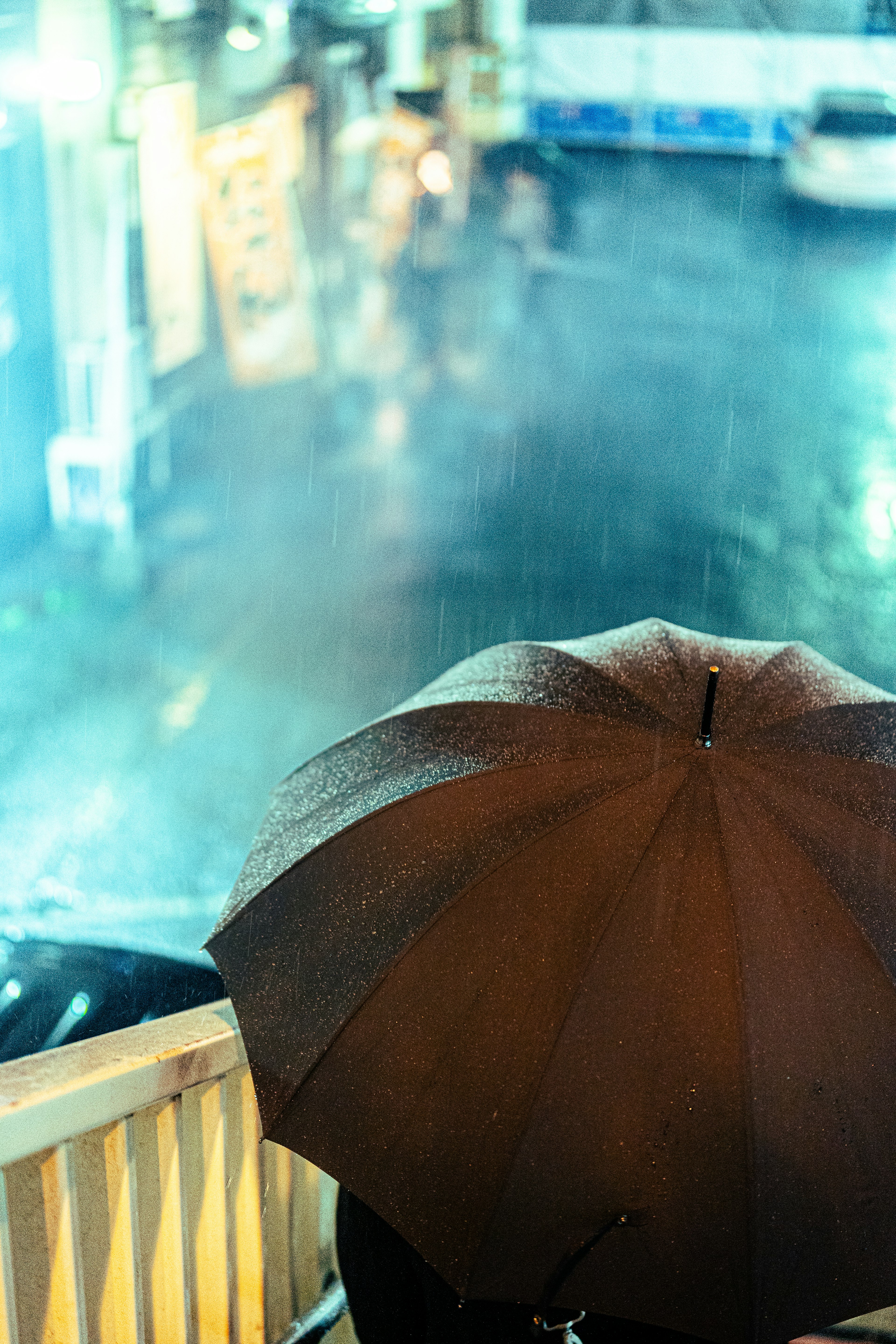 Black umbrella in the rain with a blurred city background